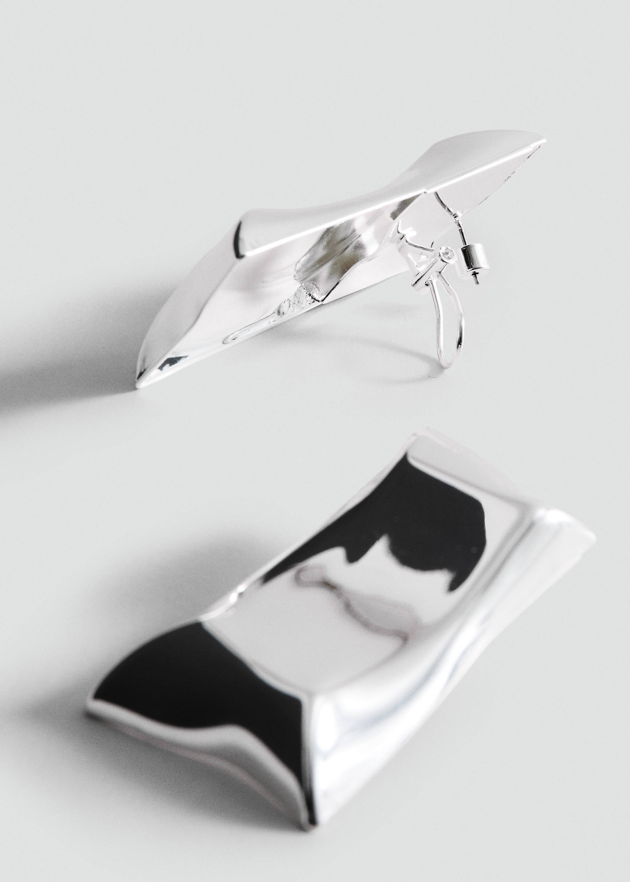 Sculptural silver-toned metallic earrings with a polished wavy rectangular design.