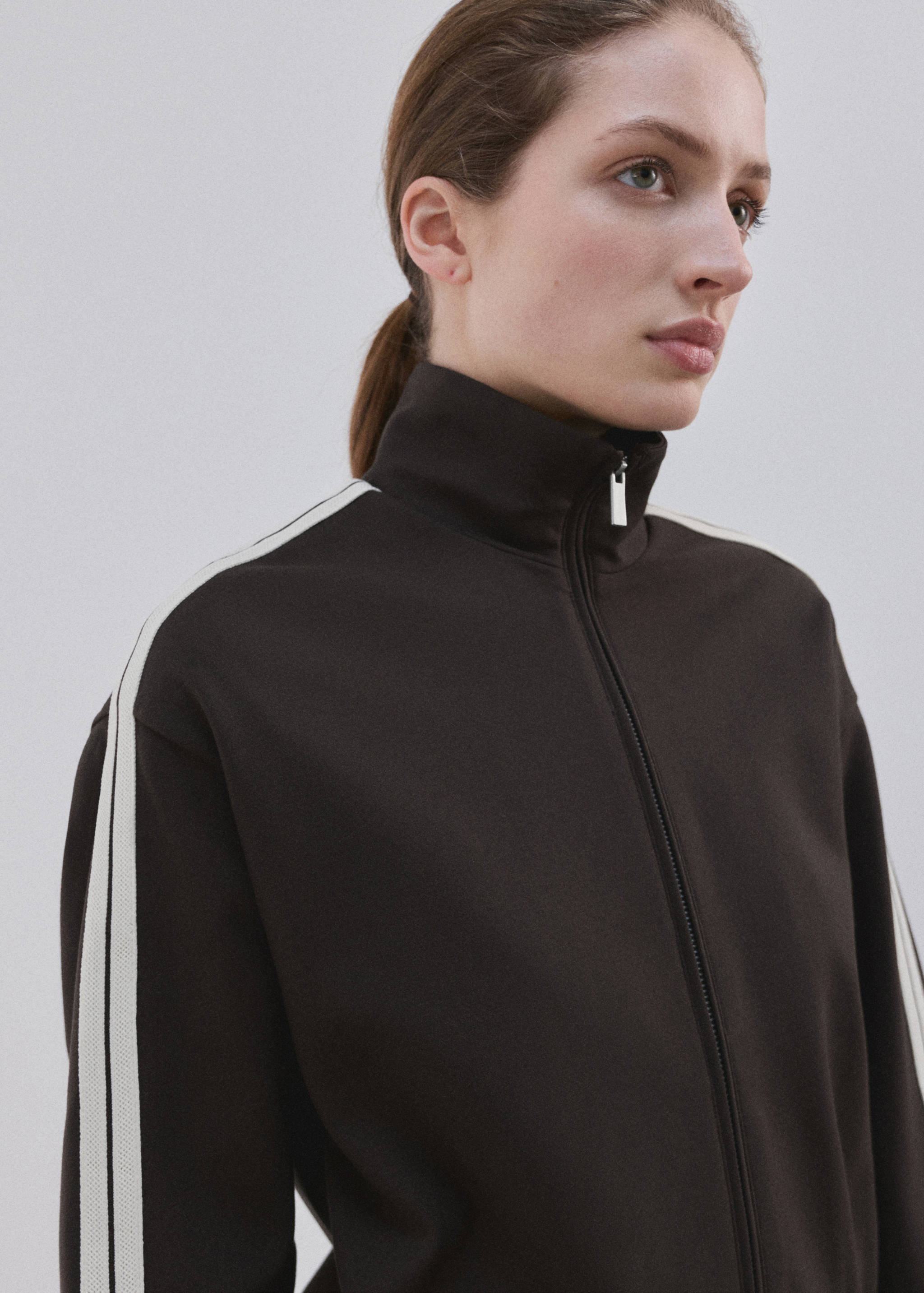 Dark brown zip-up sweatshirt with a high collar and contrasting cream sleeve stripes.