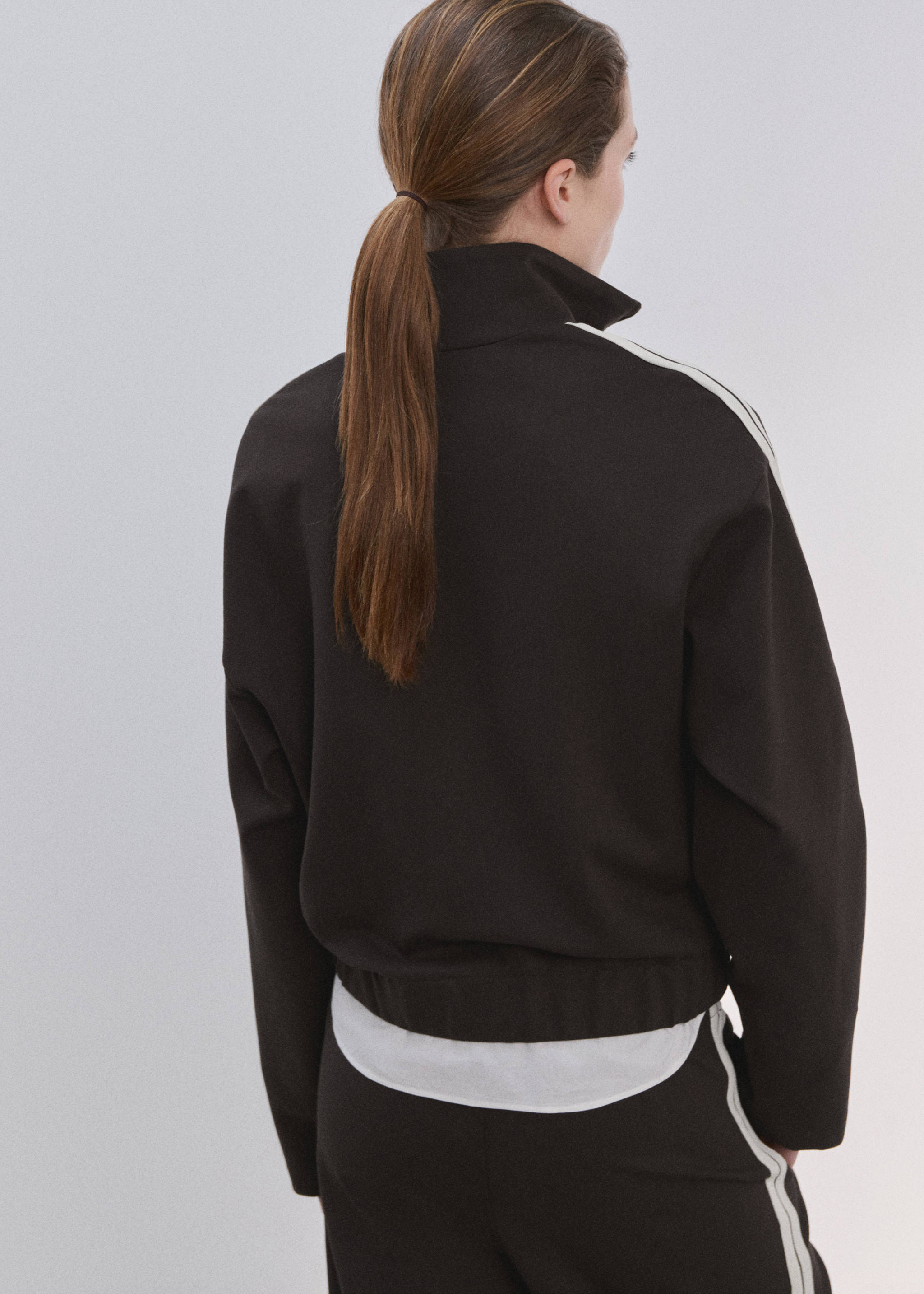 Back view of a black sweatshirt with a high neck and white stripes.