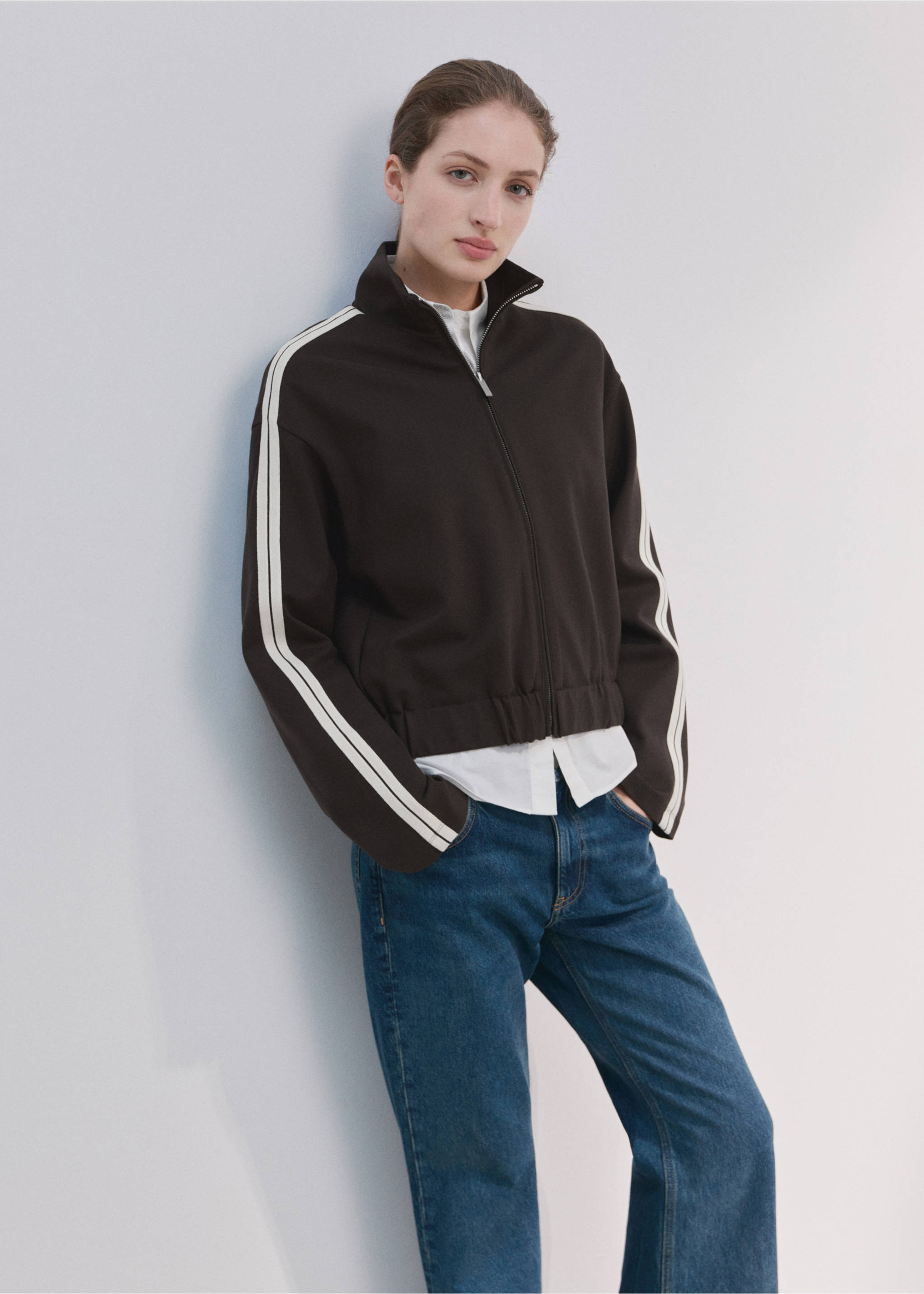 Dark brown zip-up sweatshirt with white sleeve stripes, worn over a white shirt and blue jeans., Brown. Ref: 27043306-00.