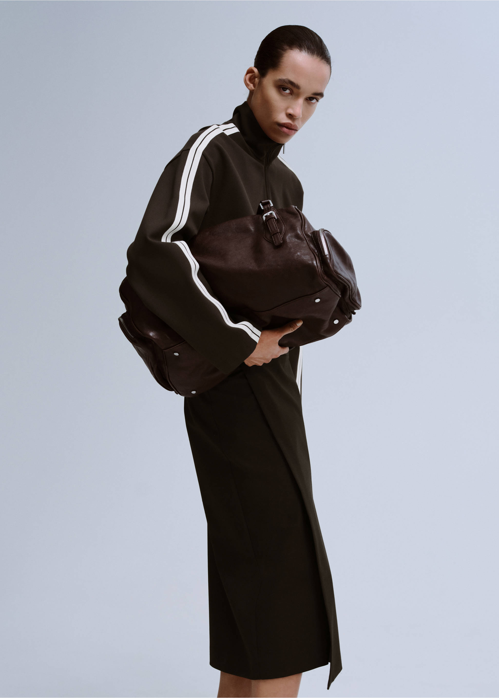 Dark olive green zip-up sweatshirt with white sleeve stripes, worn with a large brown bag., Brown. Ref: 27043306-00.