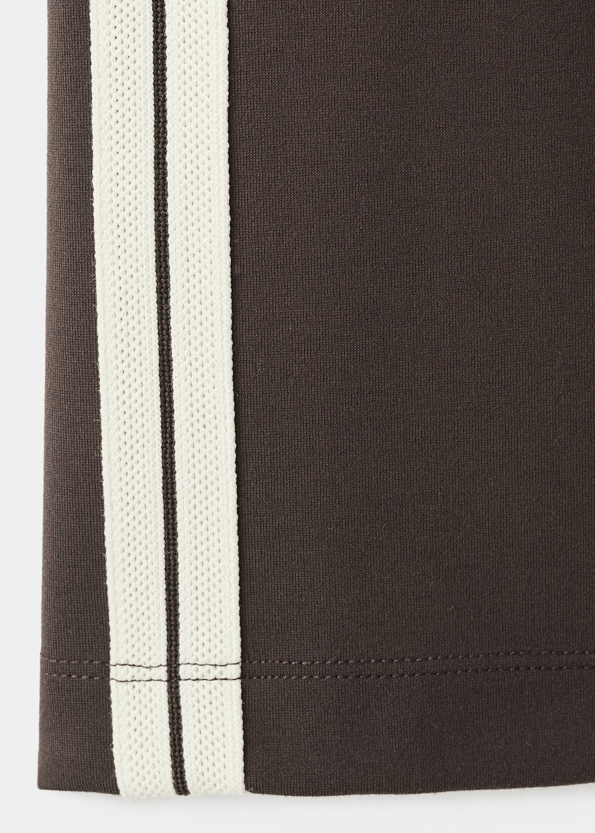 Close-up of fabric detail on a dark brown sweatshirt with off-white side stripes.