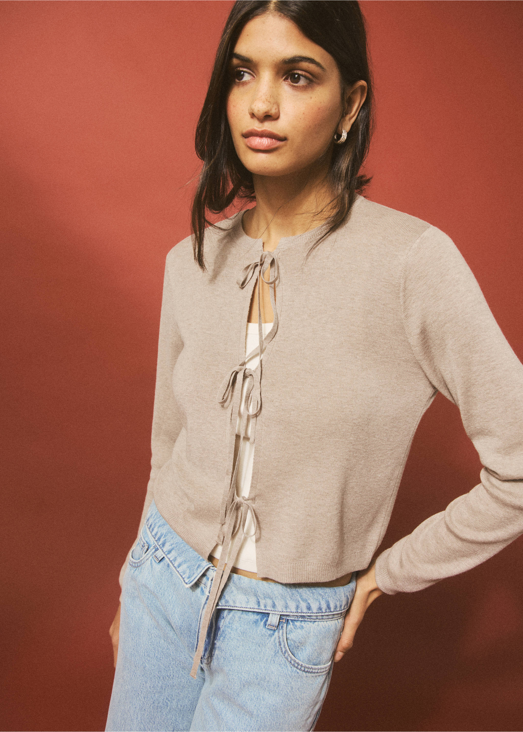 Beige knit cardigan with front ties, layered over a white top and blue jeans., Sand. Ref: 27044048-00.