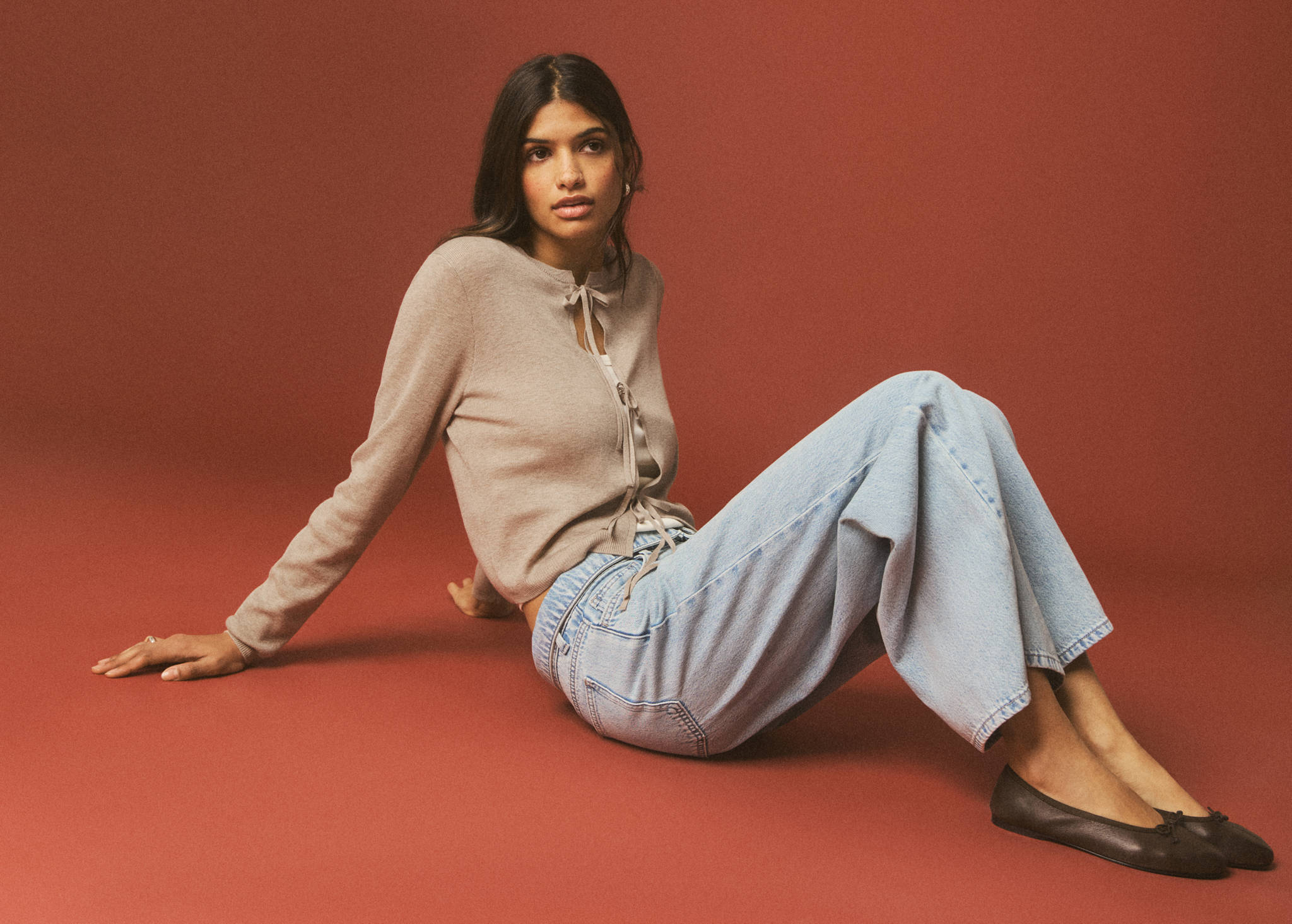 Light brown cardigan with front string ties, worn with light-blue trousers.