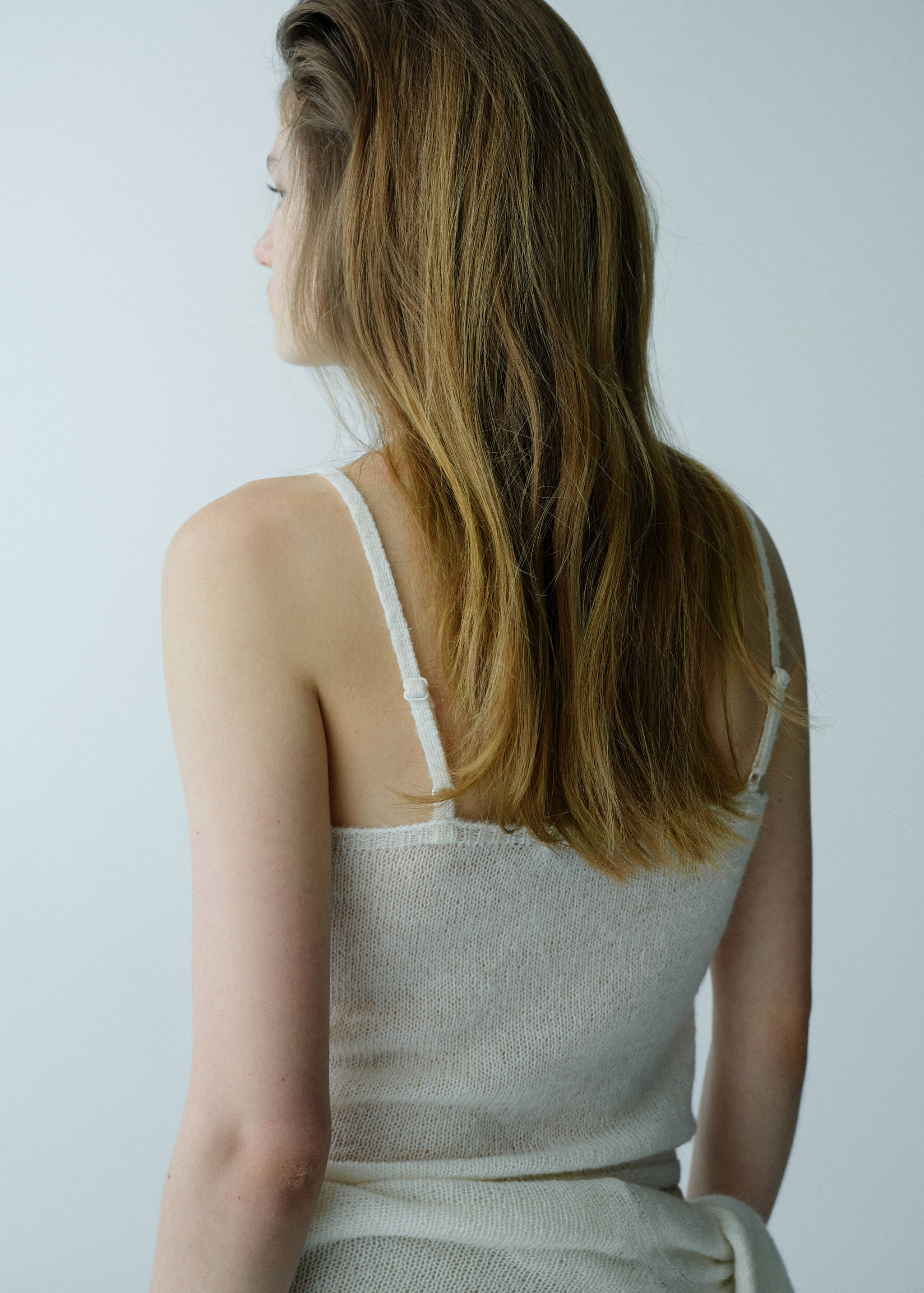Back view of a white knitted top with thin adjustable straps.