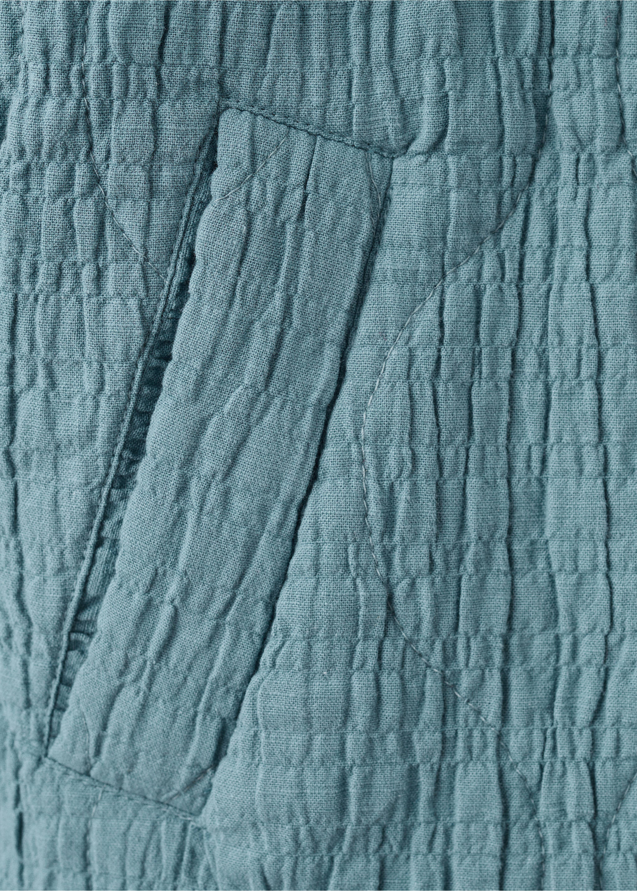 Close-up of the textured fabric and pocket detail on a teal jacket., Petrol Blue. Ref: 27045156-00.
