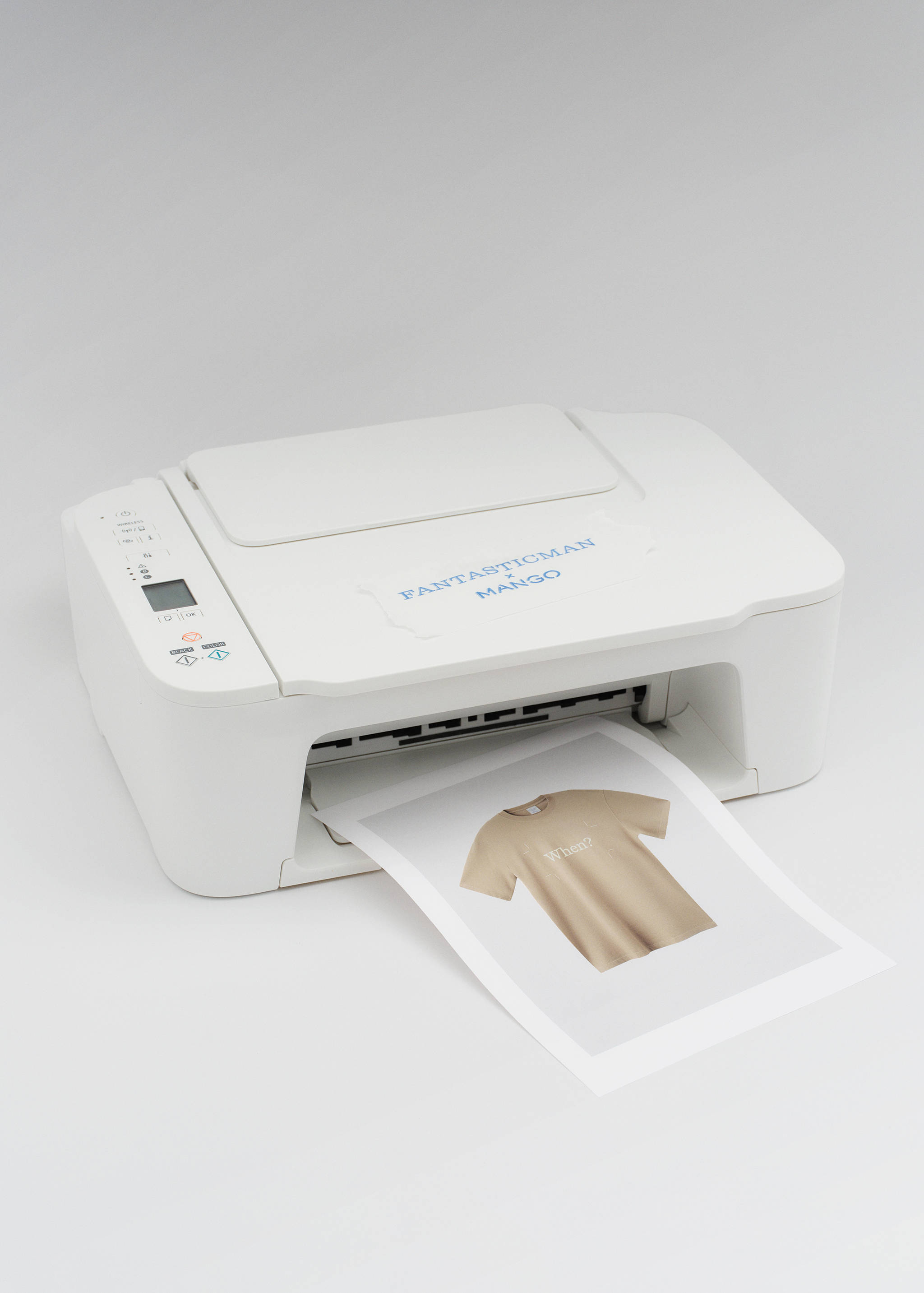 Beige short-sleeved t-shirt printed on a sheet of paper emerging from a white printer.