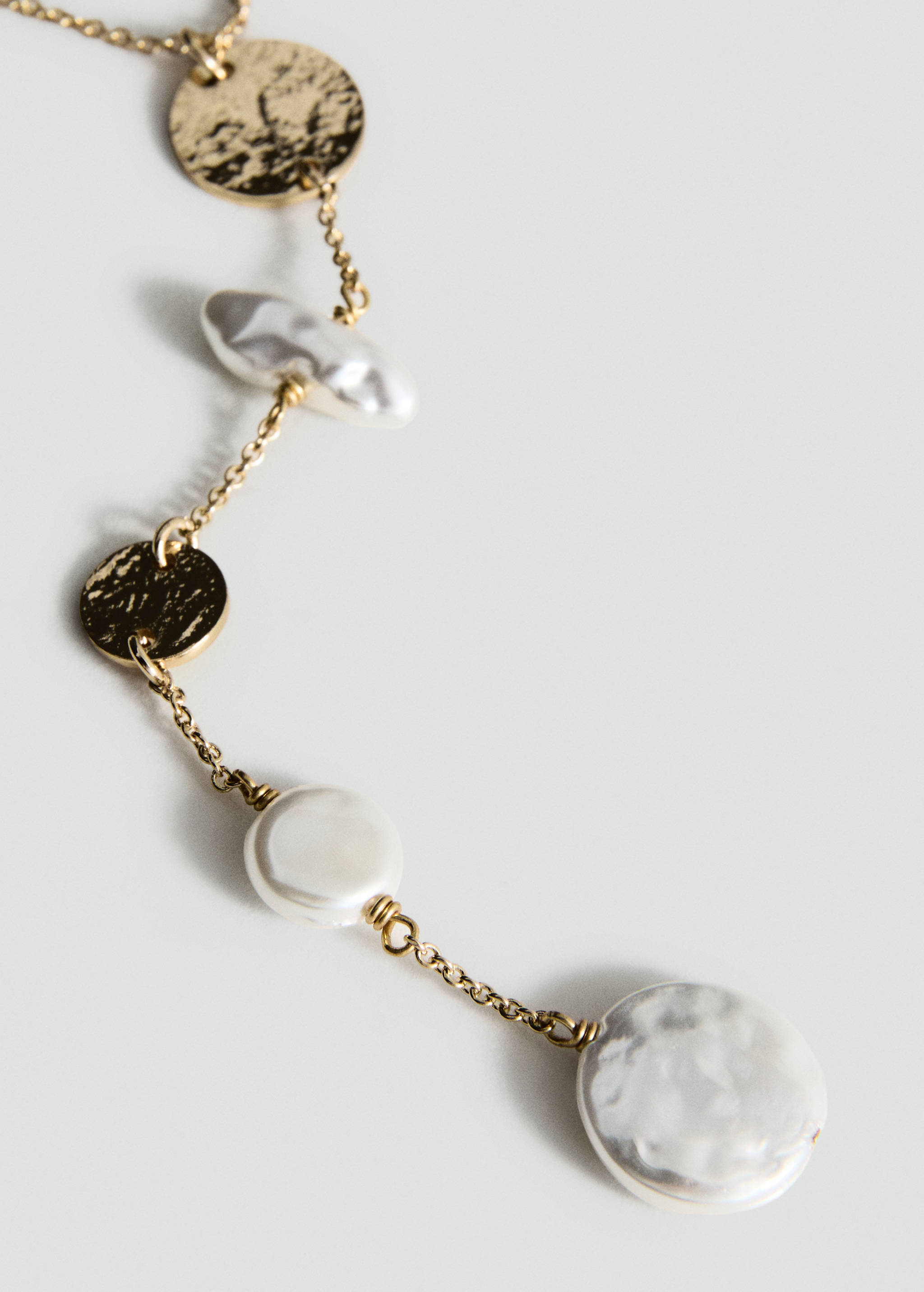 Gold-toned necklace with textured metallic discs and white beads.
