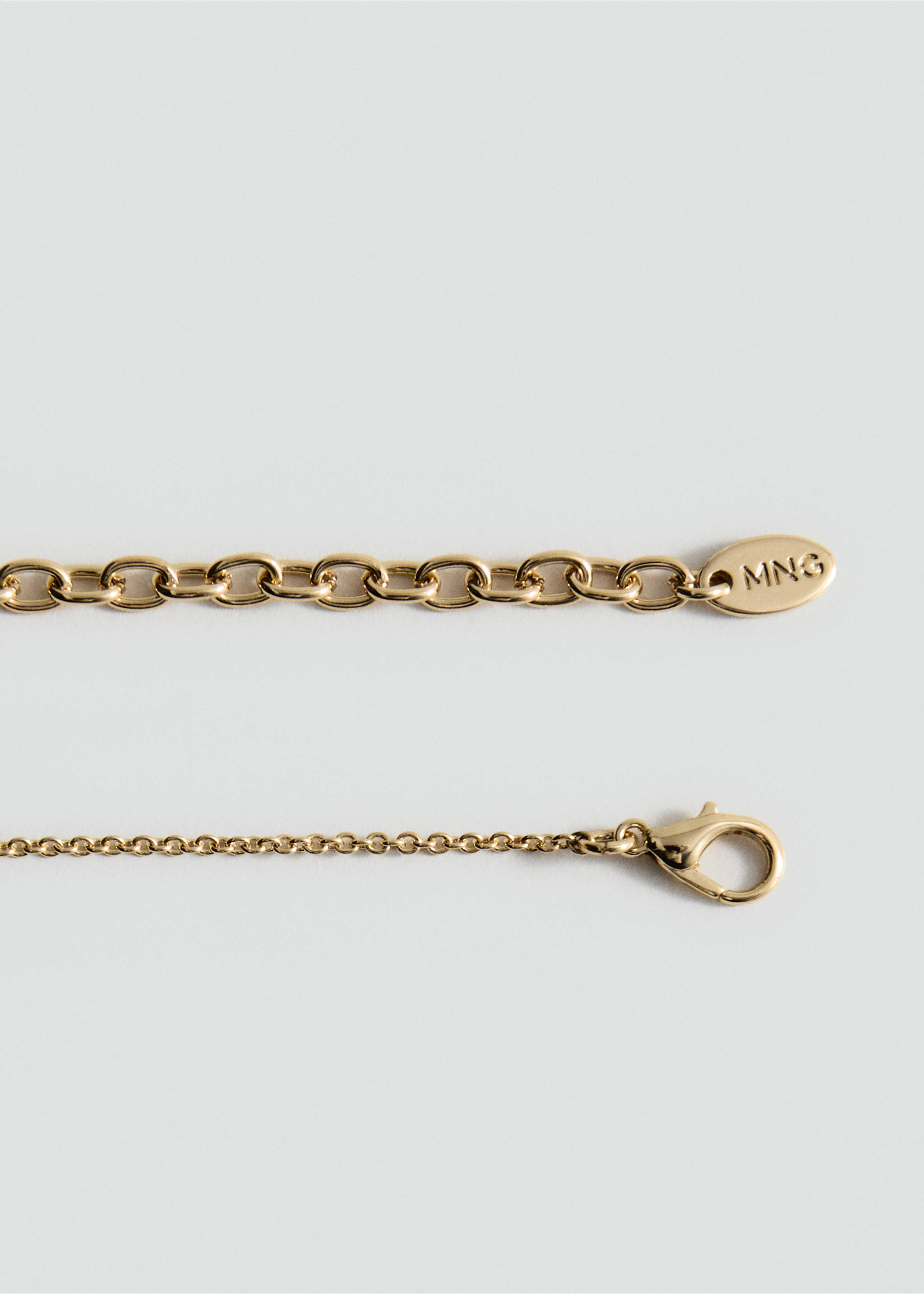 Close-up of a gold-toned metal collar chain with an MNG engraved tag and lobster clasp., Gold. Ref: 27045991-00.