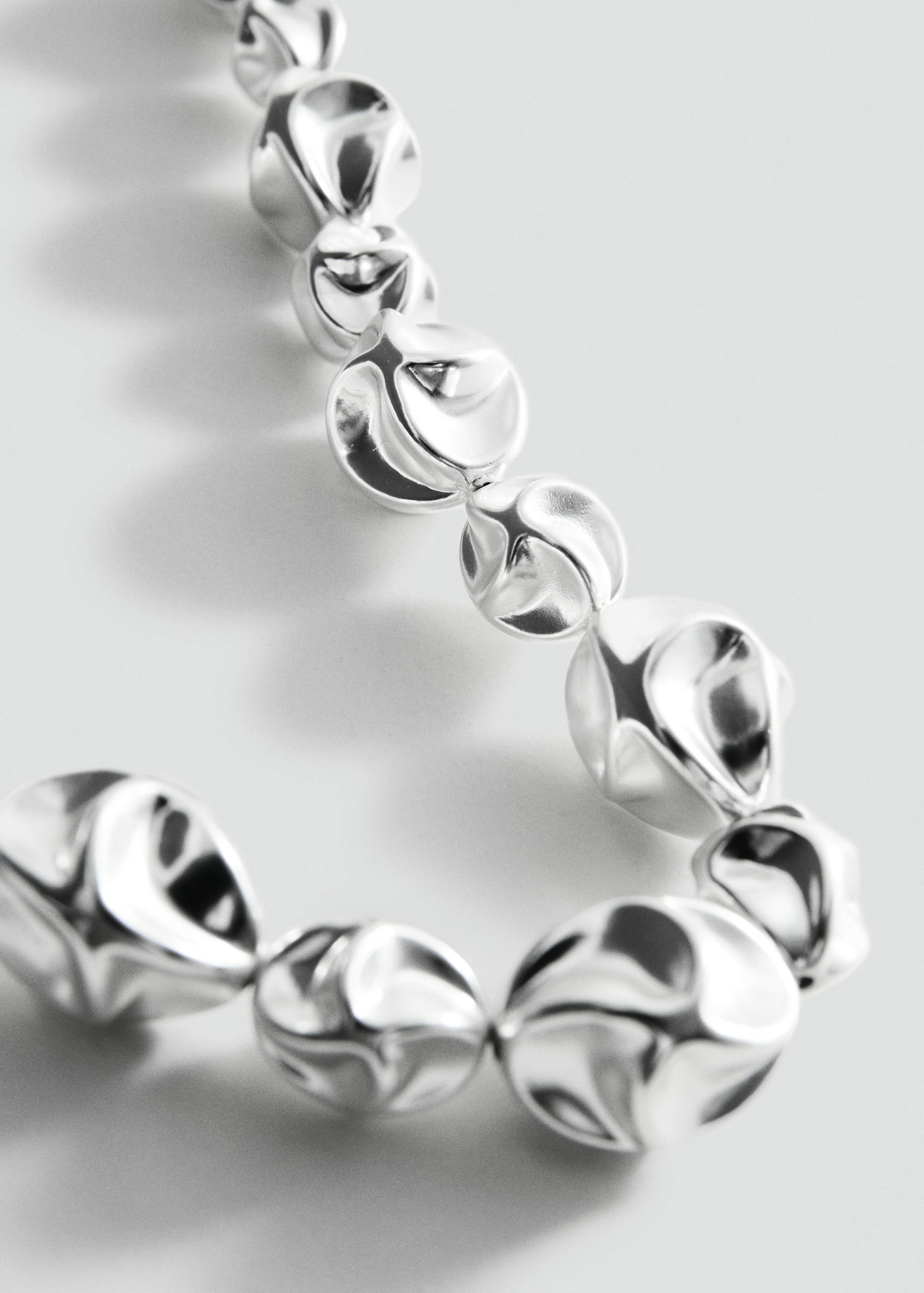 Silver necklace with irregular metallic beads, close-up view.