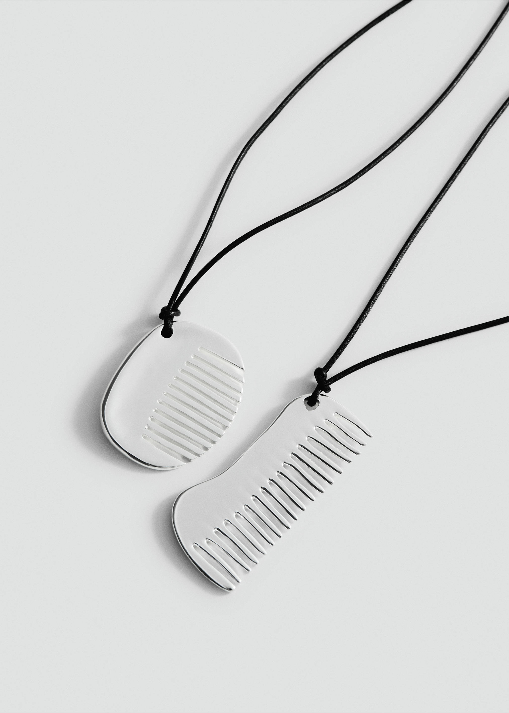 Silver-coloured comb pendant necklaces on black cords., Silver. Ref: 27047799-00.
