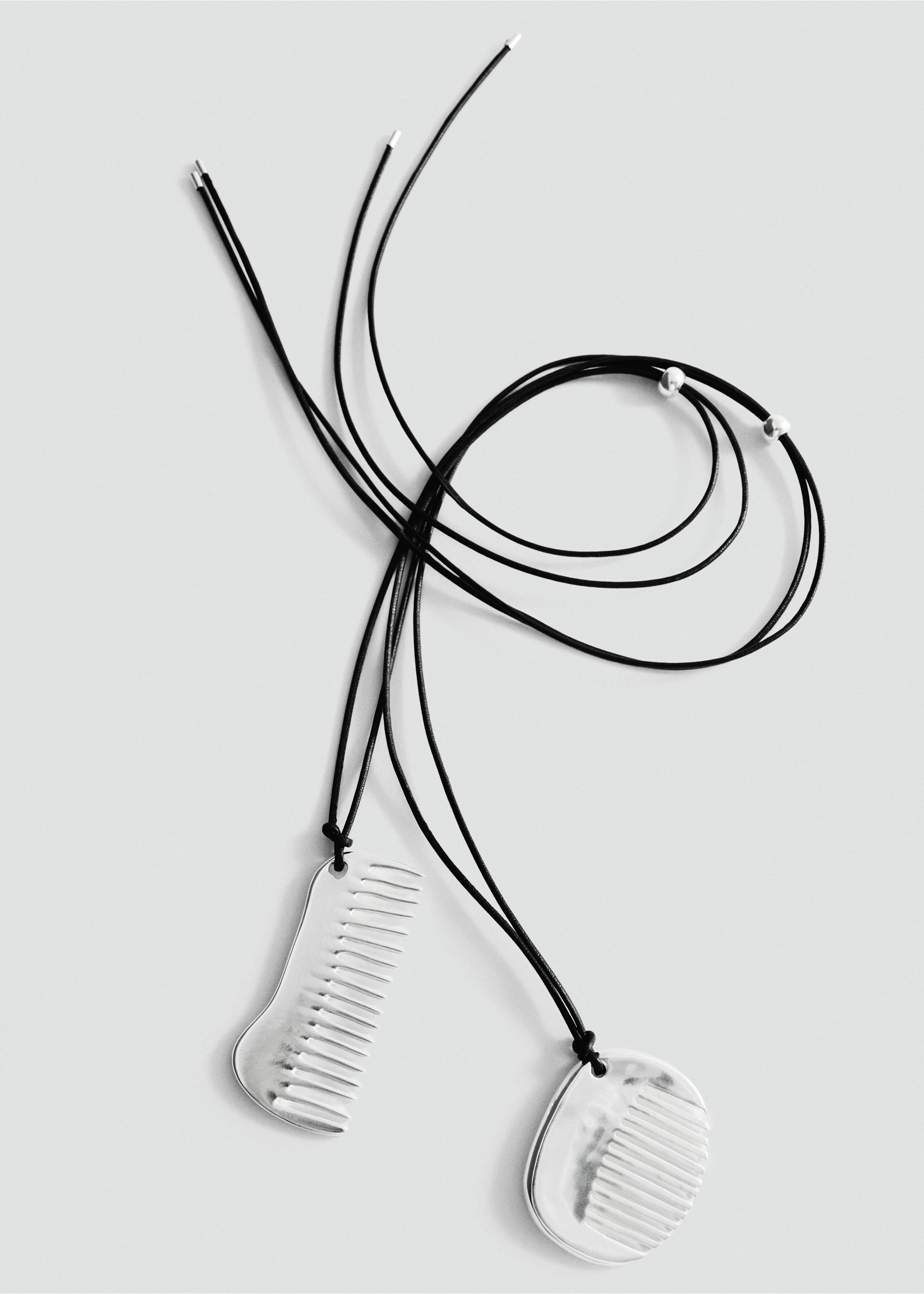 Silver comb pendant necklace on black cords., Silver. Ref: 27047799-00.