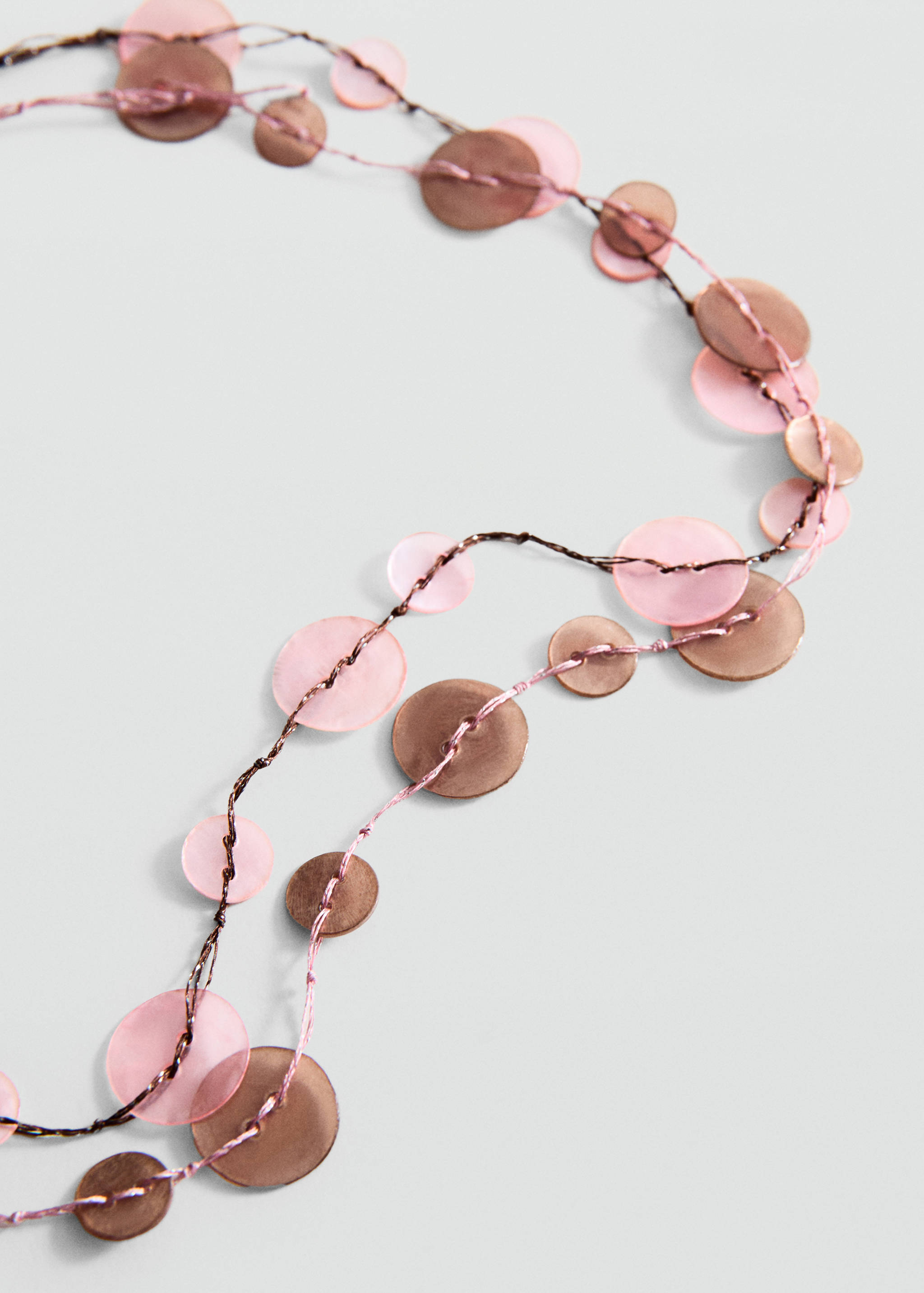 Close-up of a multi-strand necklace with pink and bronze disc beads.