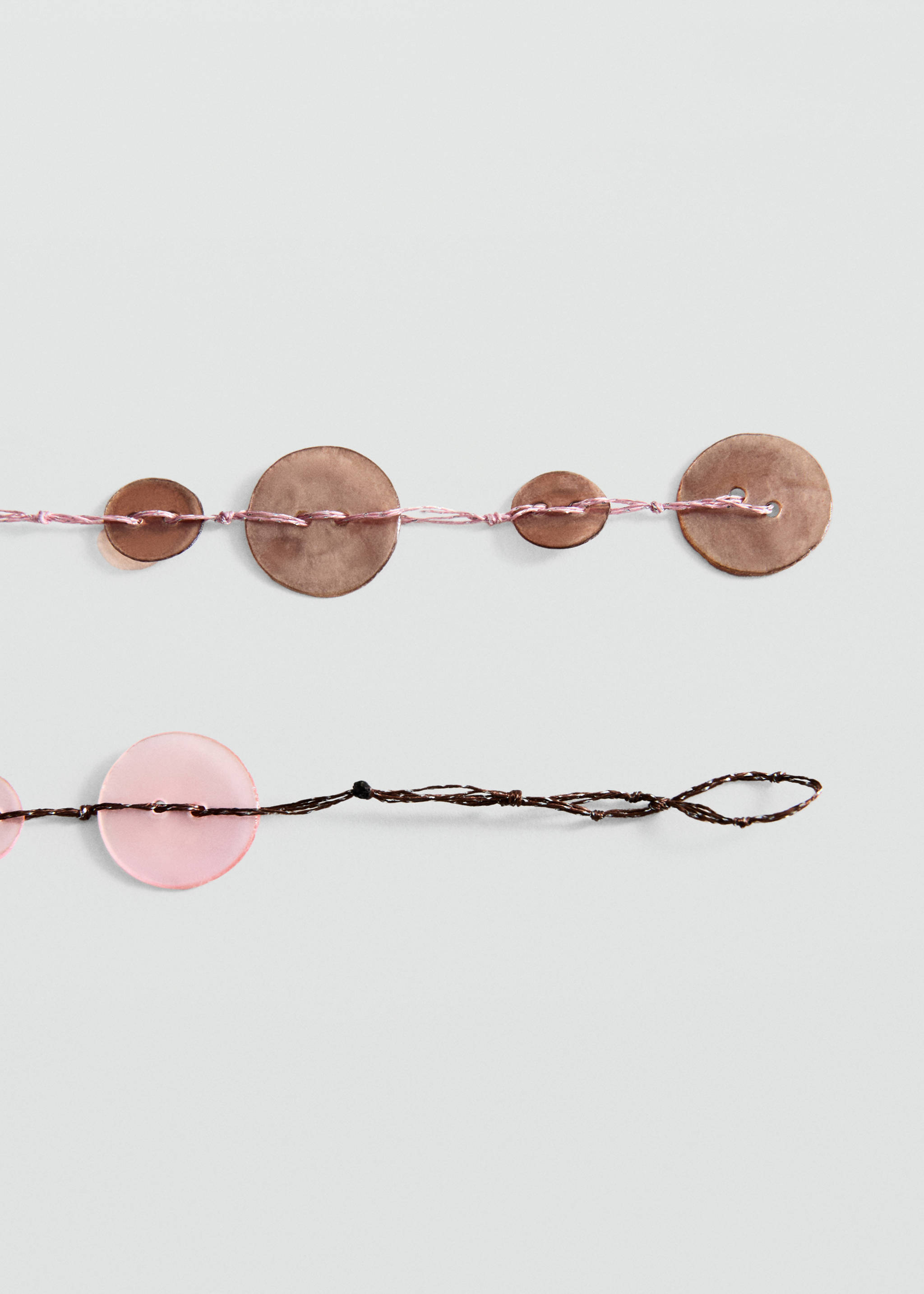 Close-up of a beaded collar accessory with threads and circular pieces.