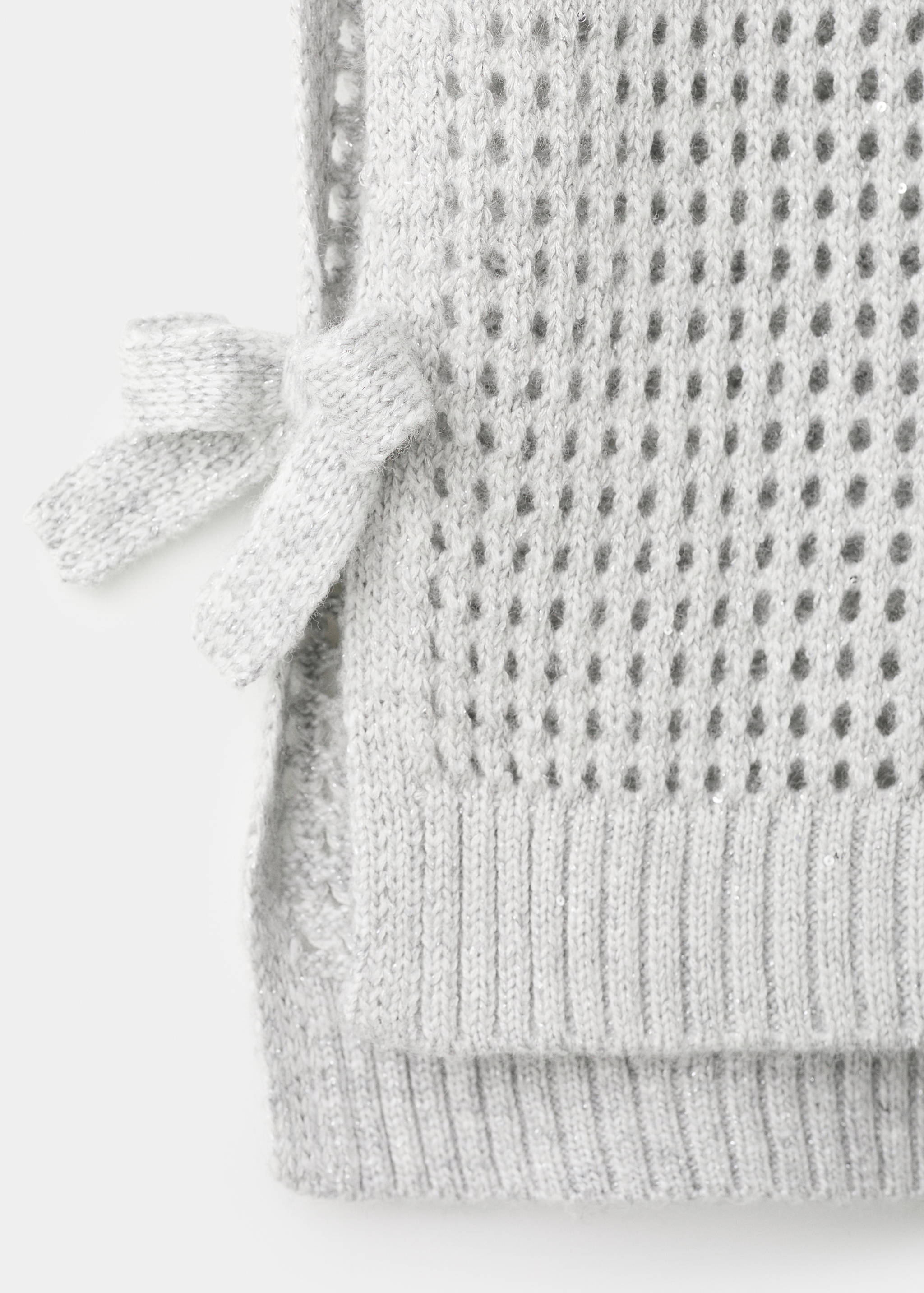 Close-up of a grey knitted vest with mesh texture and side bow.