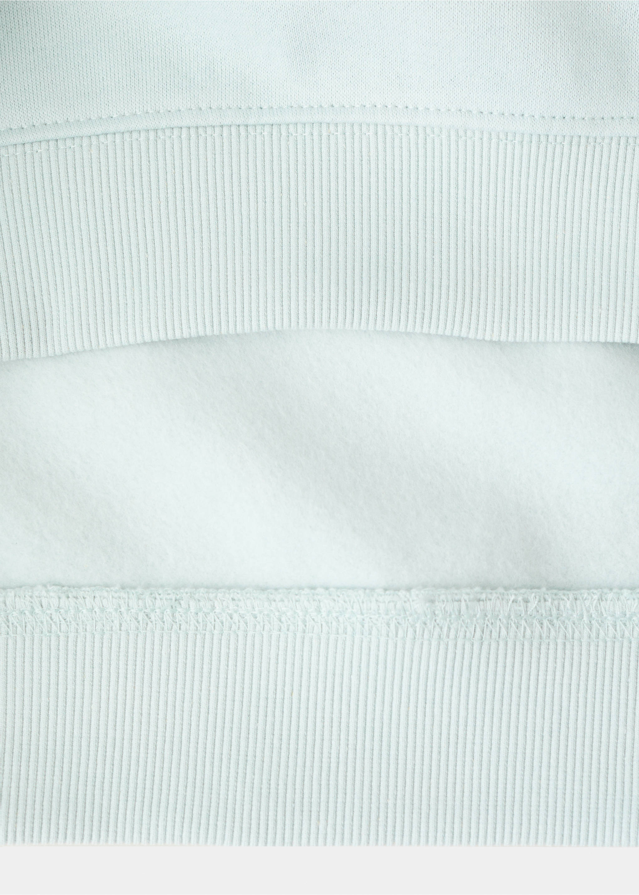 Close-up of the fabric texture and ribbed hem of a light blue sweatshirt., Aqua Green. Ref: 27051187-00.