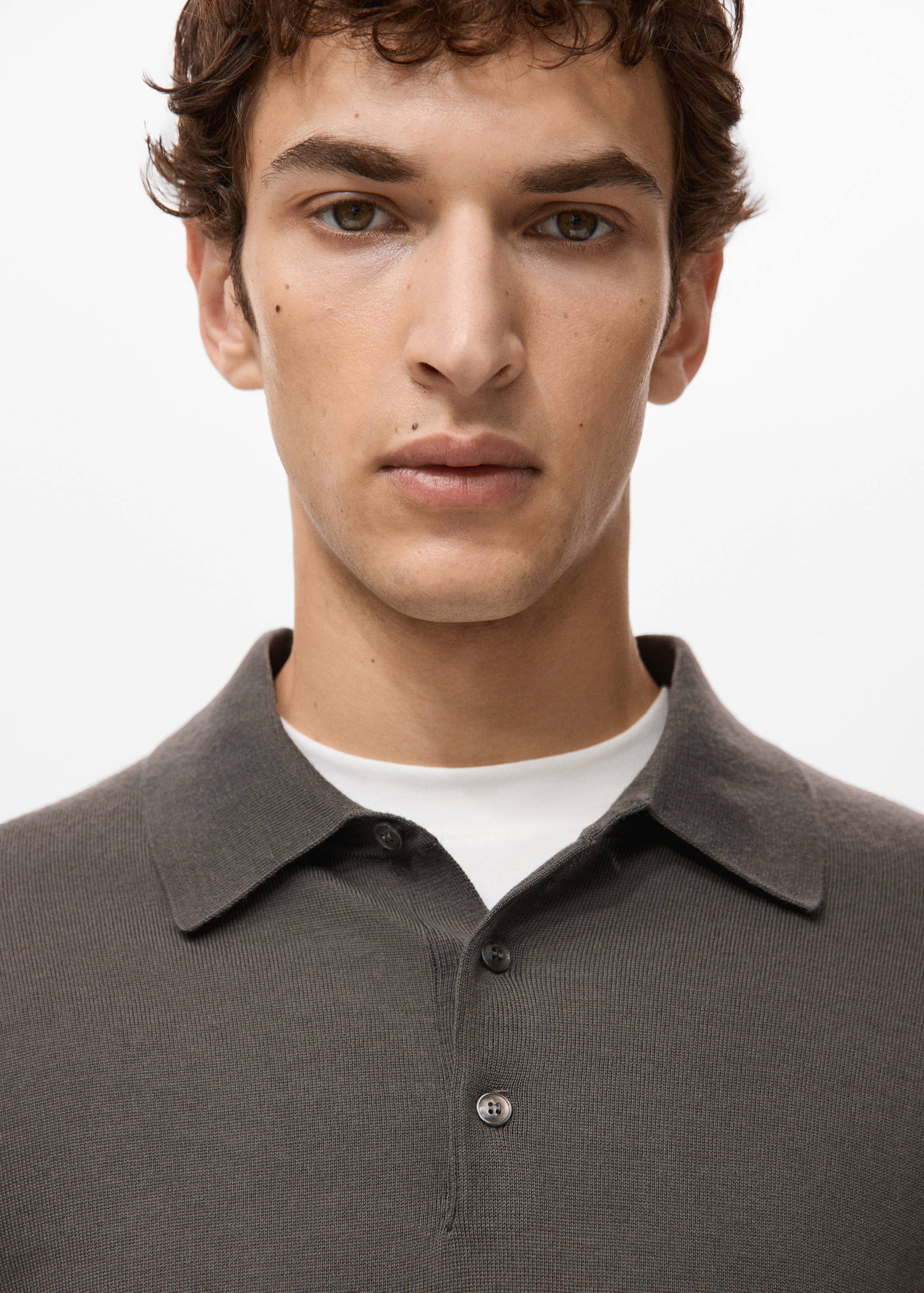 Close-up of a dark grey knitted polo shirt collar and placket on a model.