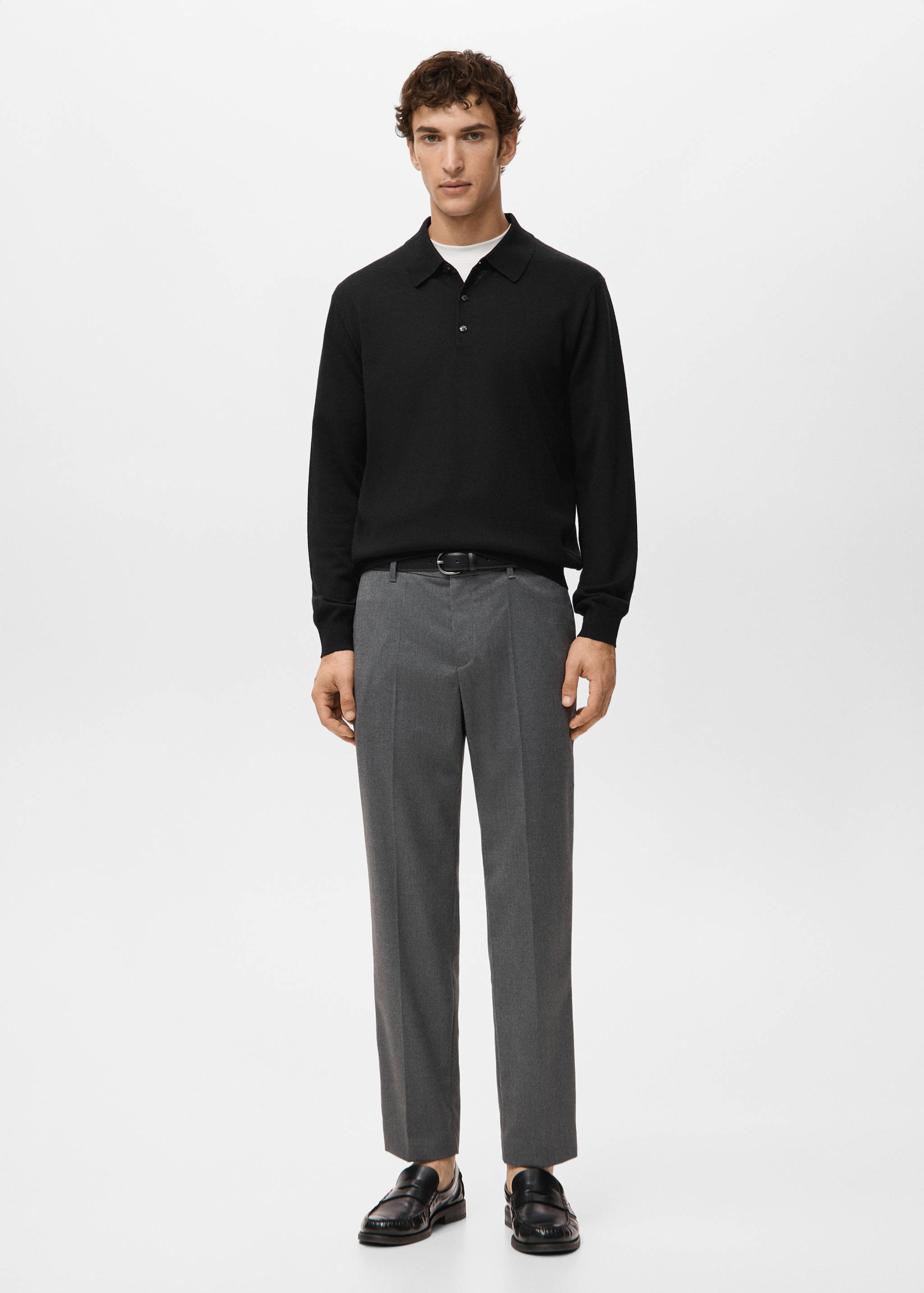 Black long-sleeved knit polo shirt worn with grey trousers.