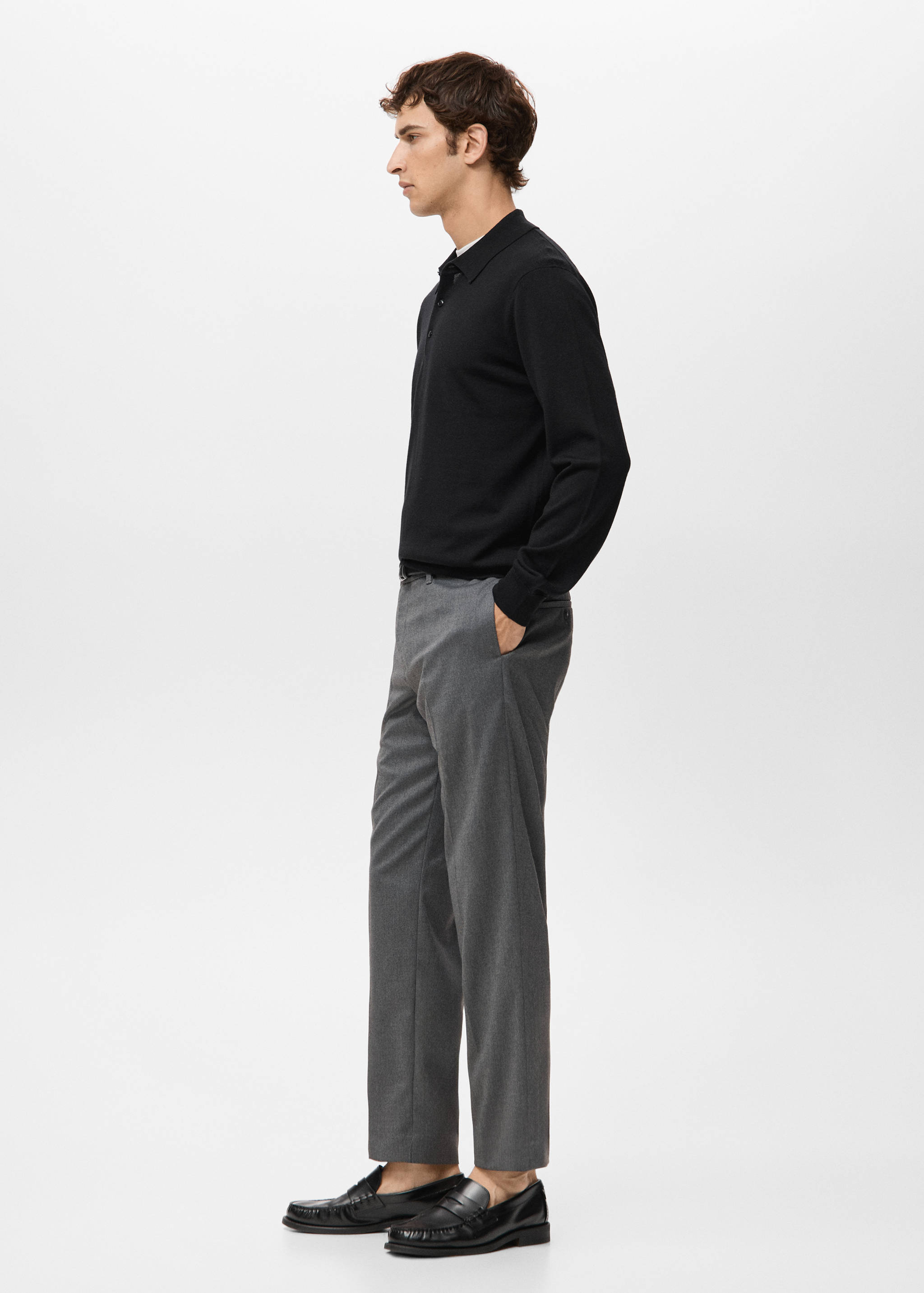 Black long-sleeved knit polo shirt worn with grey trousers.