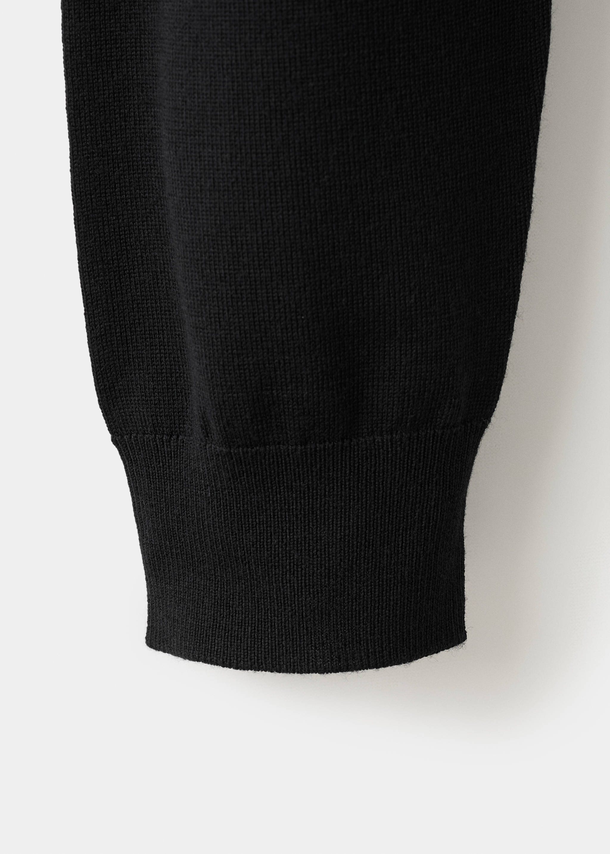 Close-up of a black polo sleeve with a ribbed cuff.