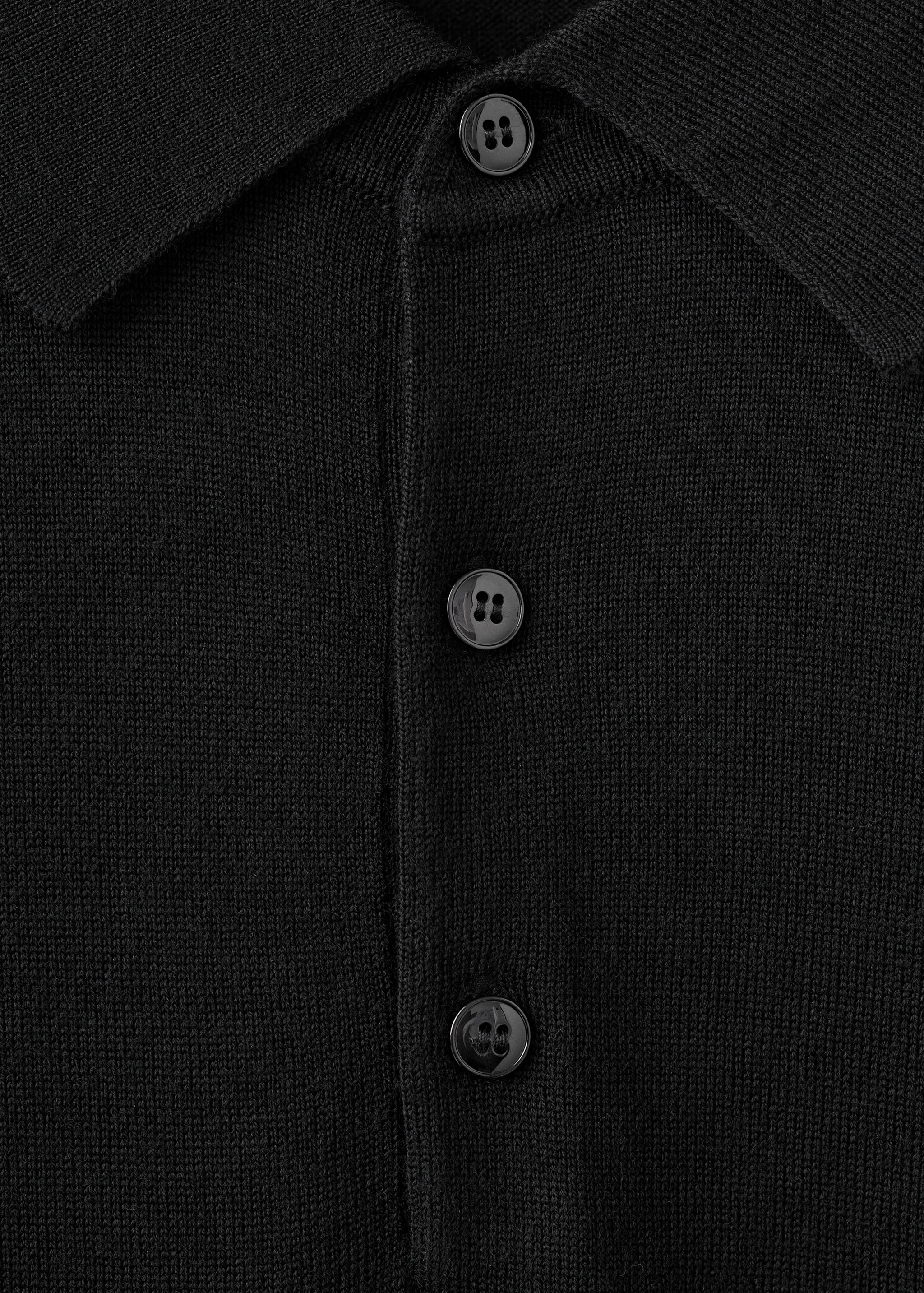 Close-up of a black knit polo shirt showing the collar and button placket.