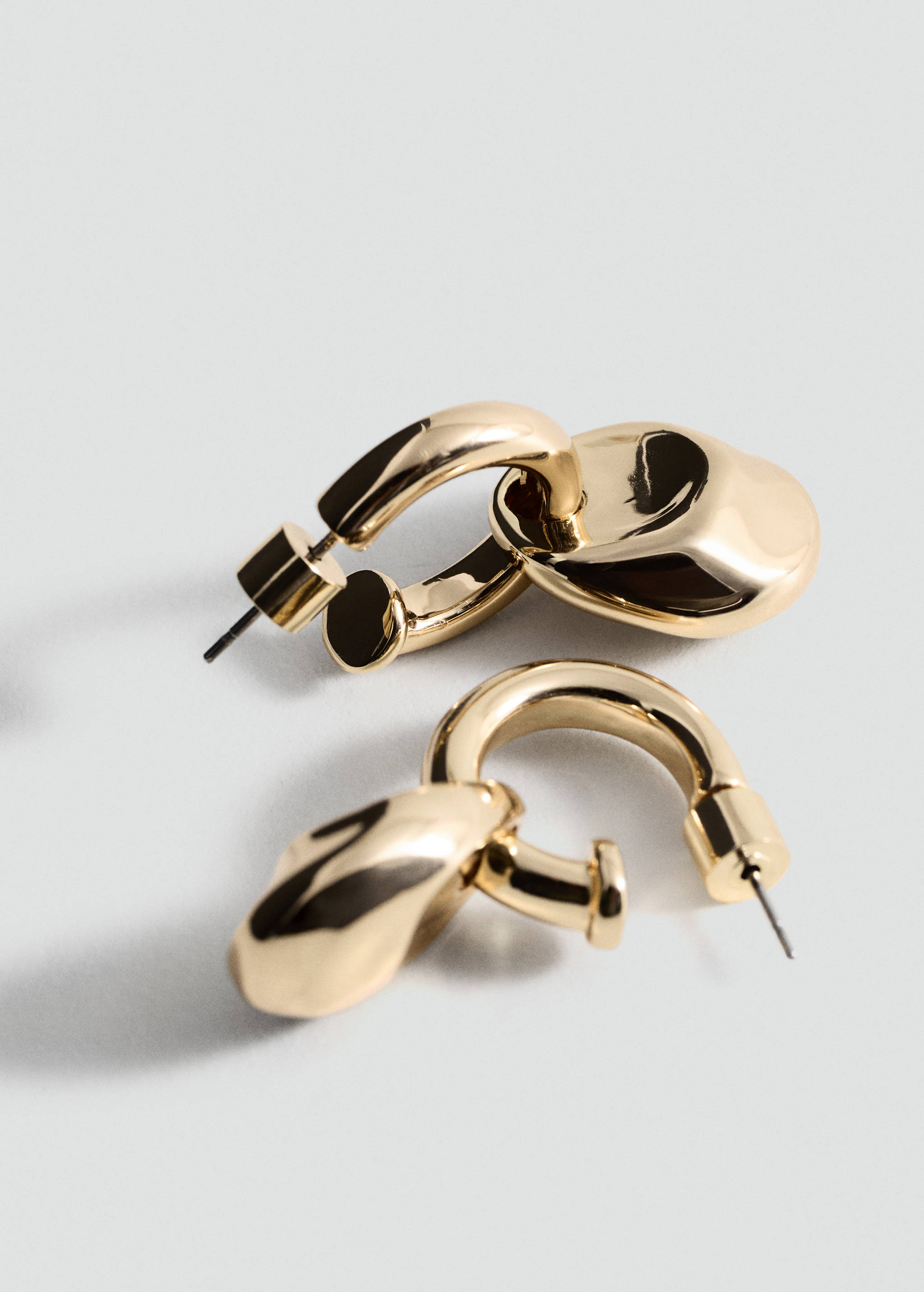 Gold-coloured metal earrings with a thick hoop and organic-shaped pendant.