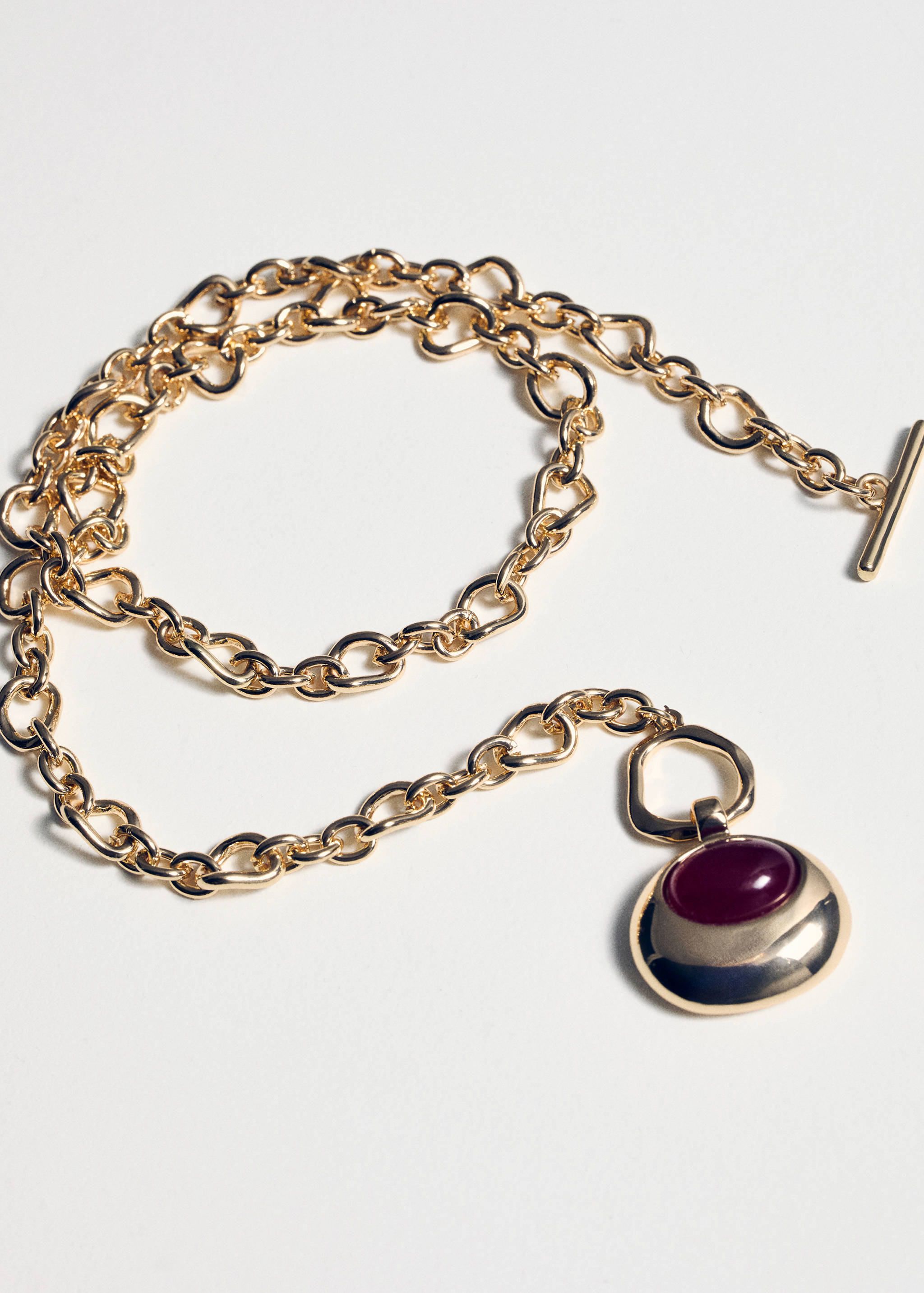 Gold-tone chain collar necklace with a red stone pendant.