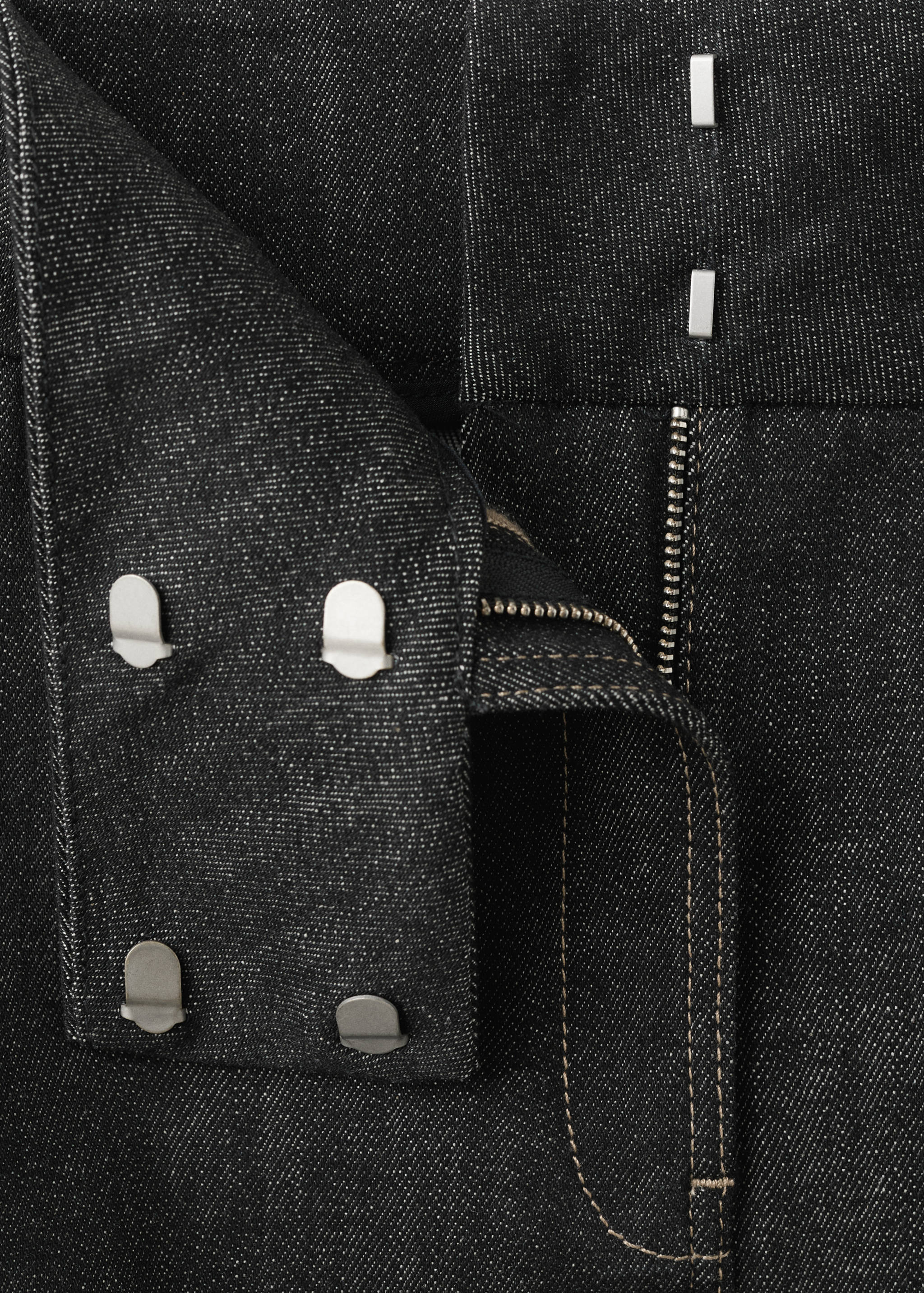 Detalle de la cinturilla y la cremallera de la falda vaquera en gris oscuro.