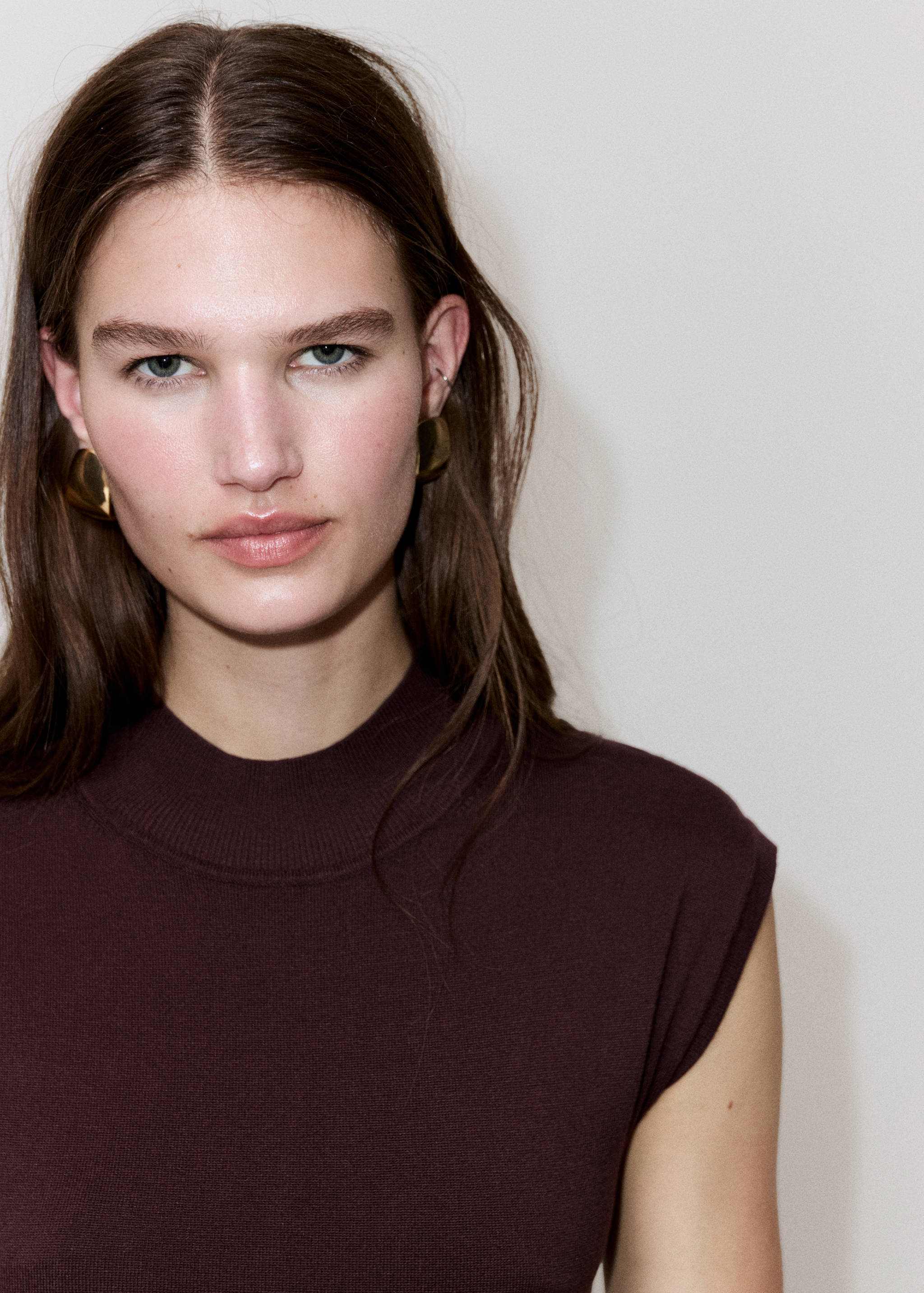 Close-up of a model wearing a dark brown sleeveless mock-neck dress.