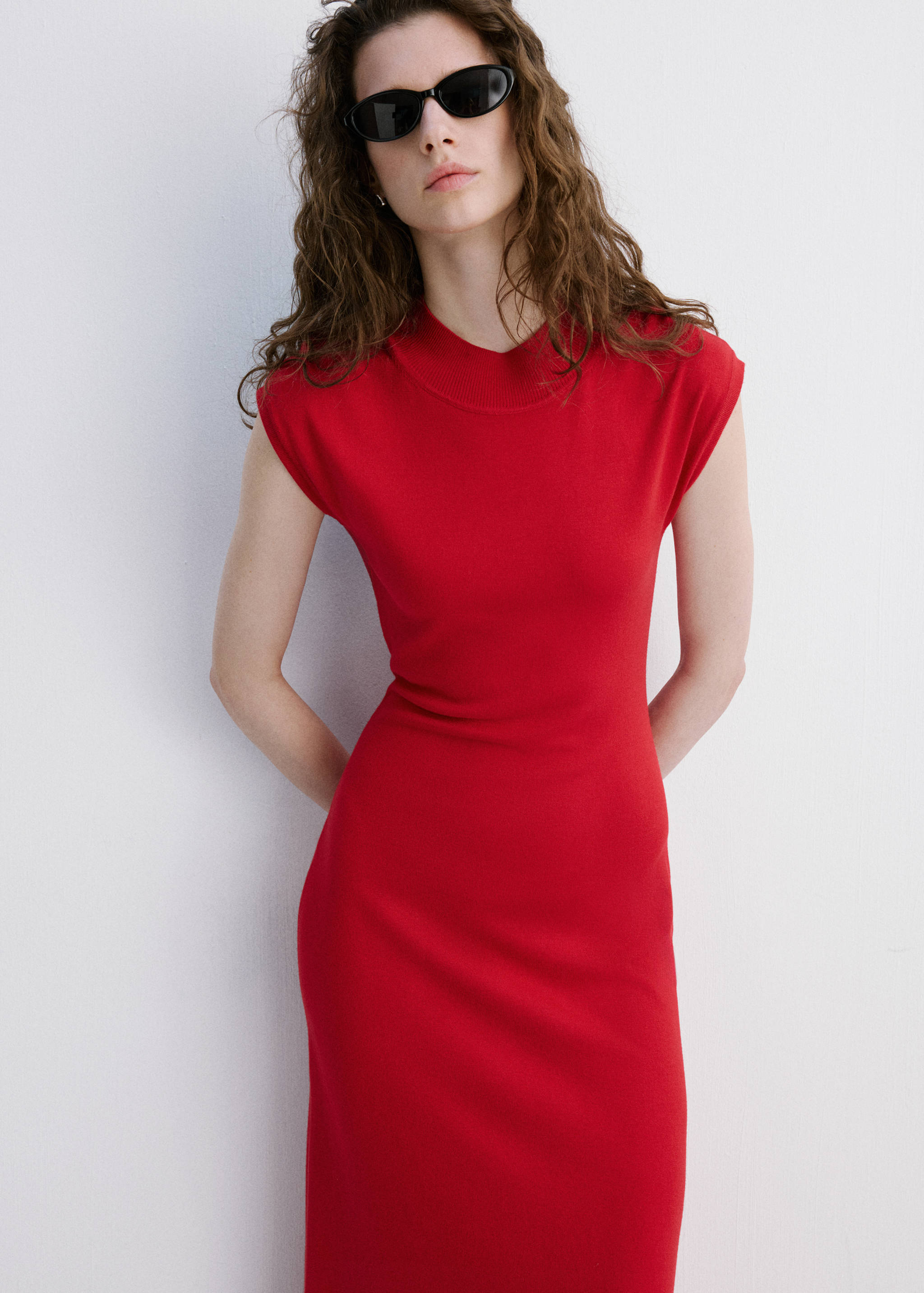 Red knitted dress with a high neckline and sleeveless fitted silhouette.