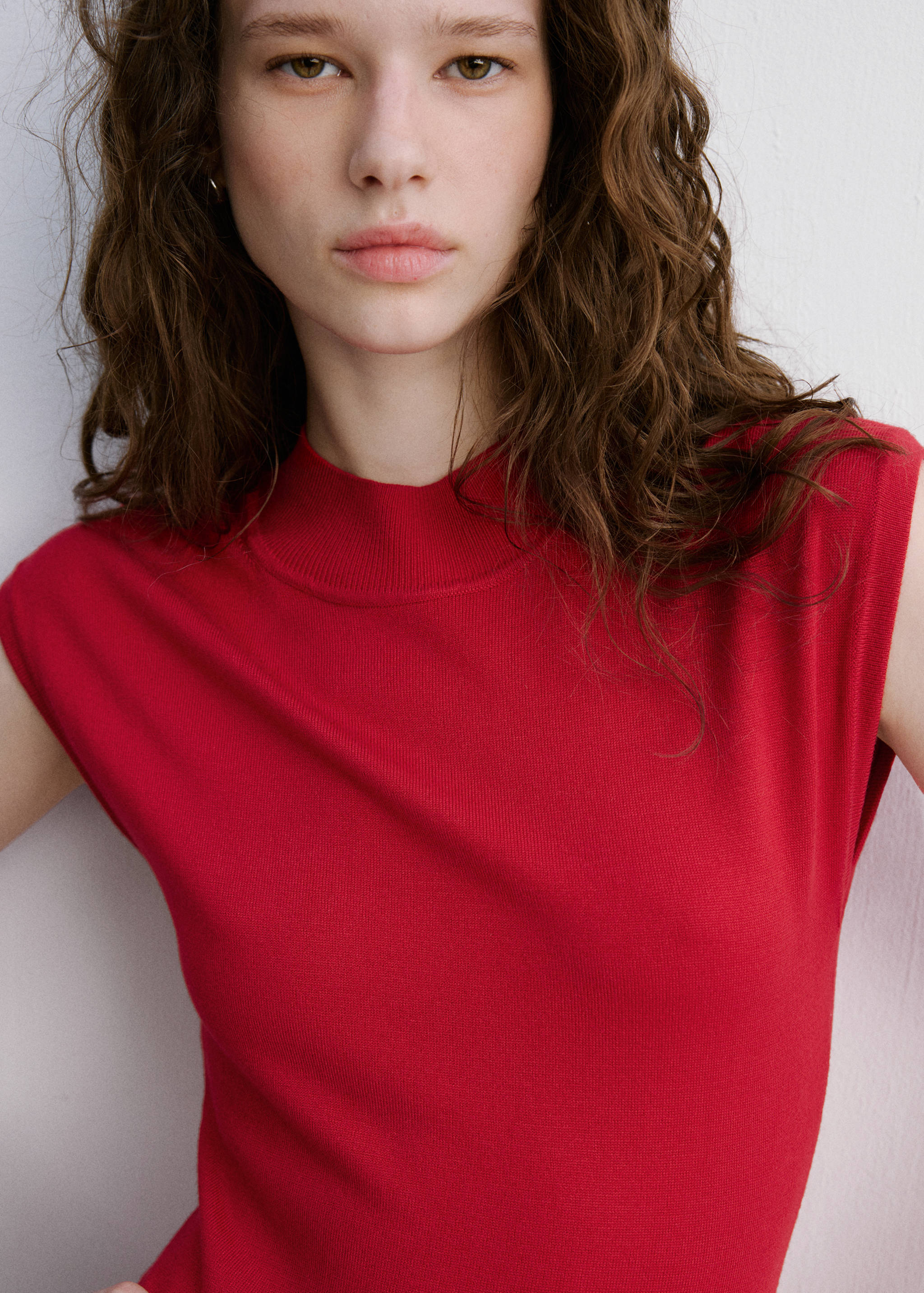 Close-up of a red knitted dress with a mock neckline.