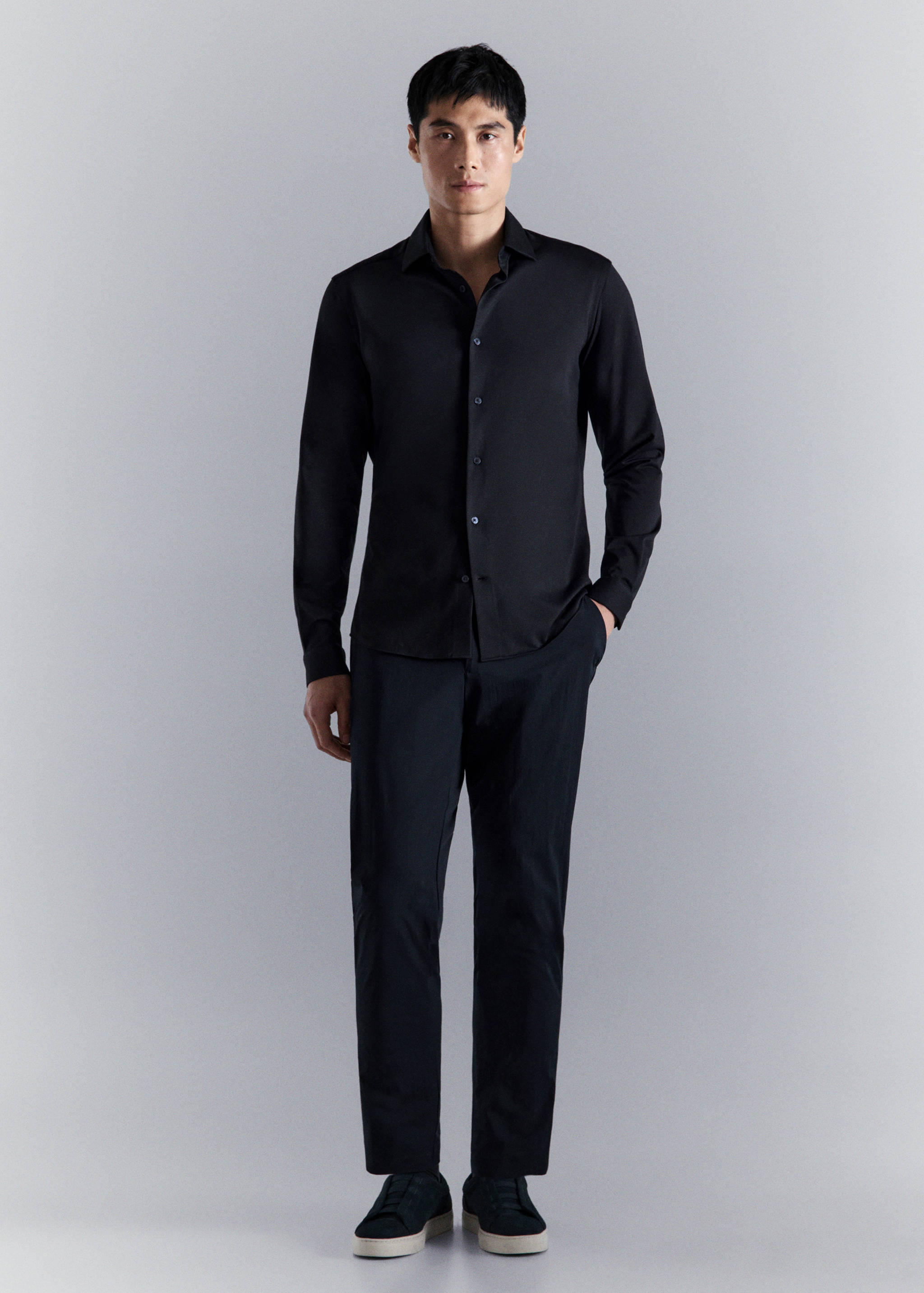 Black long-sleeved shirt with a classic collar and button fastening, worn with matching trousers.