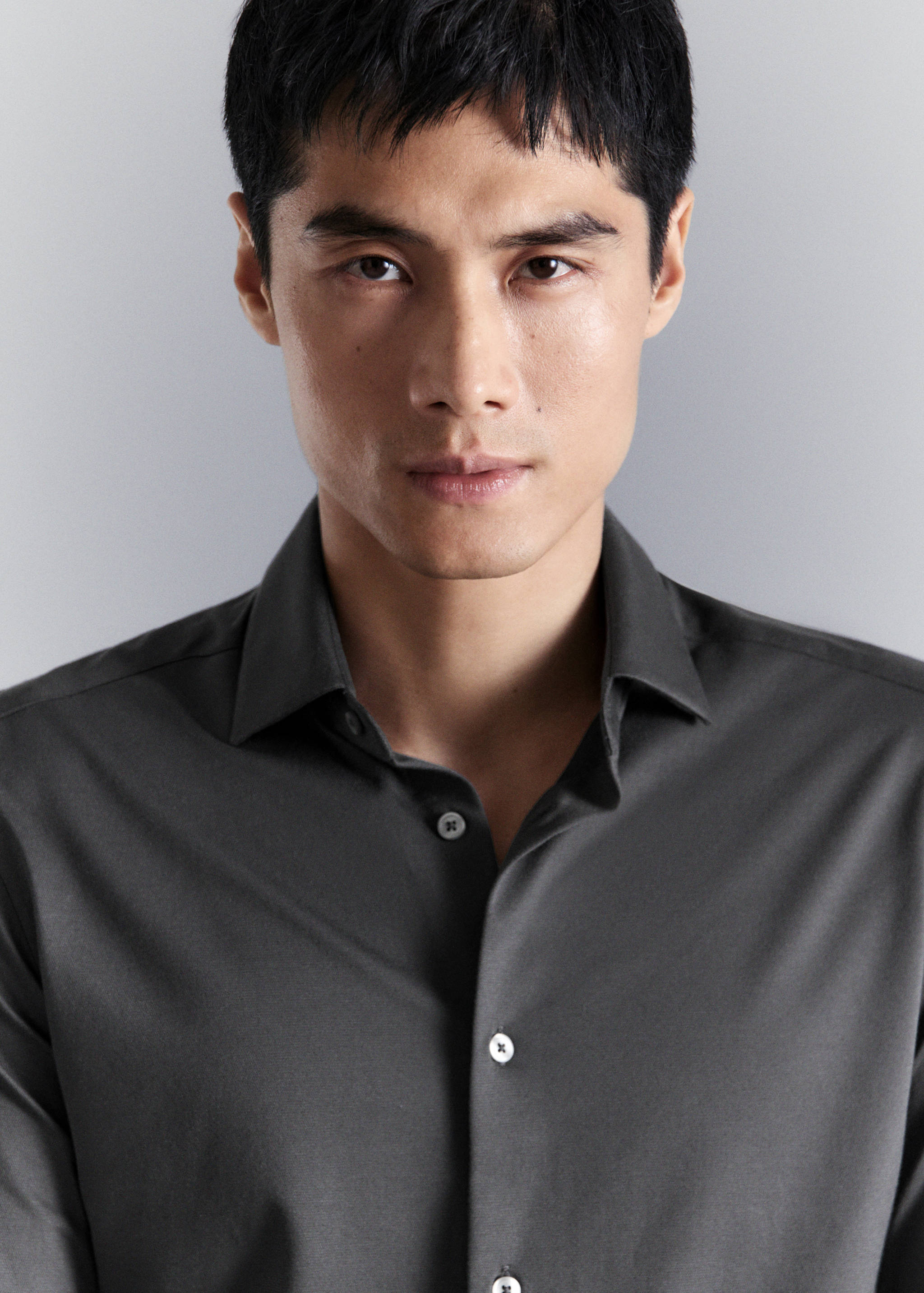 Dark grey shirt with classic collar in a close-up portrait view.