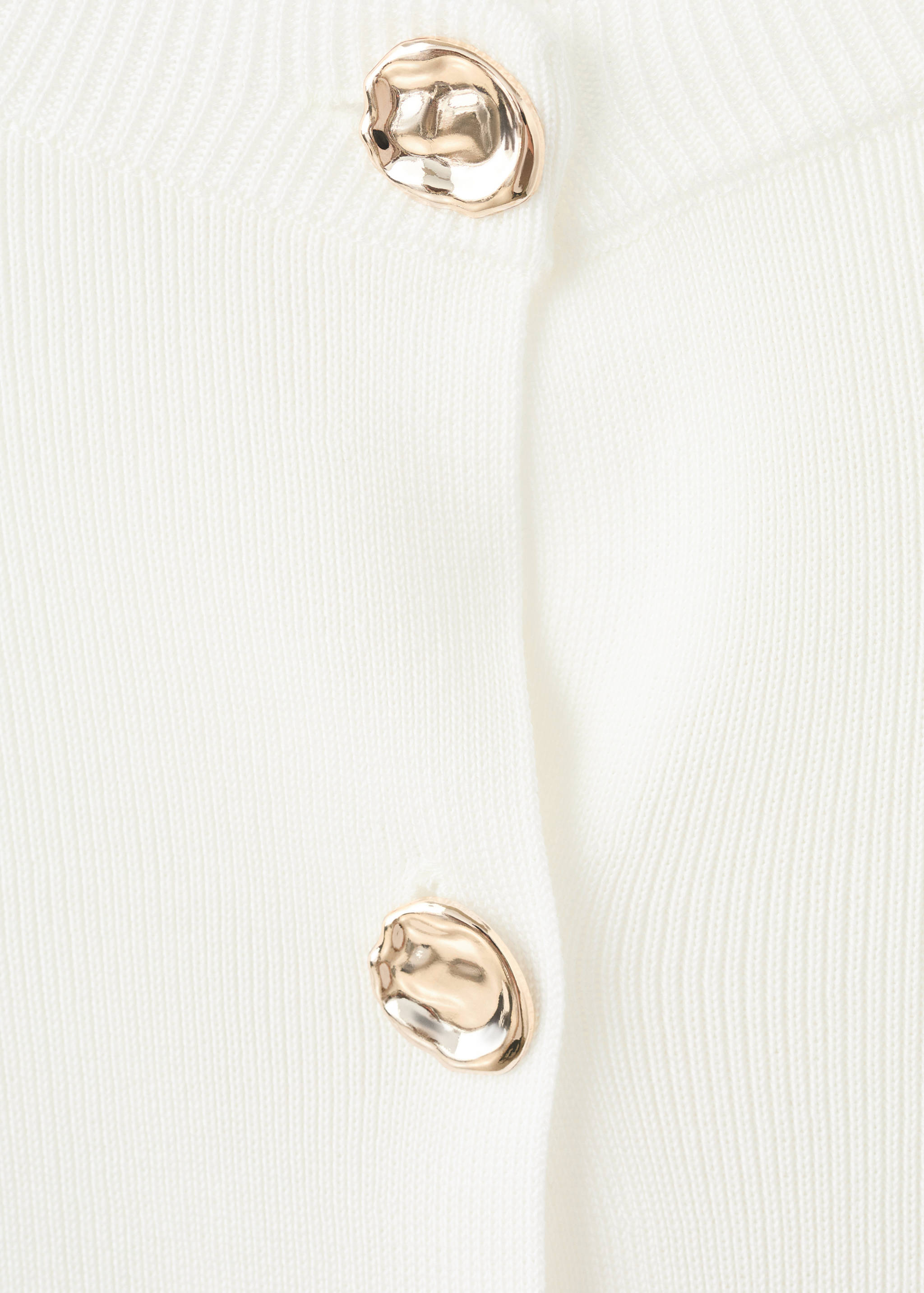 White knitted cardigan detail with metallic gold buttons