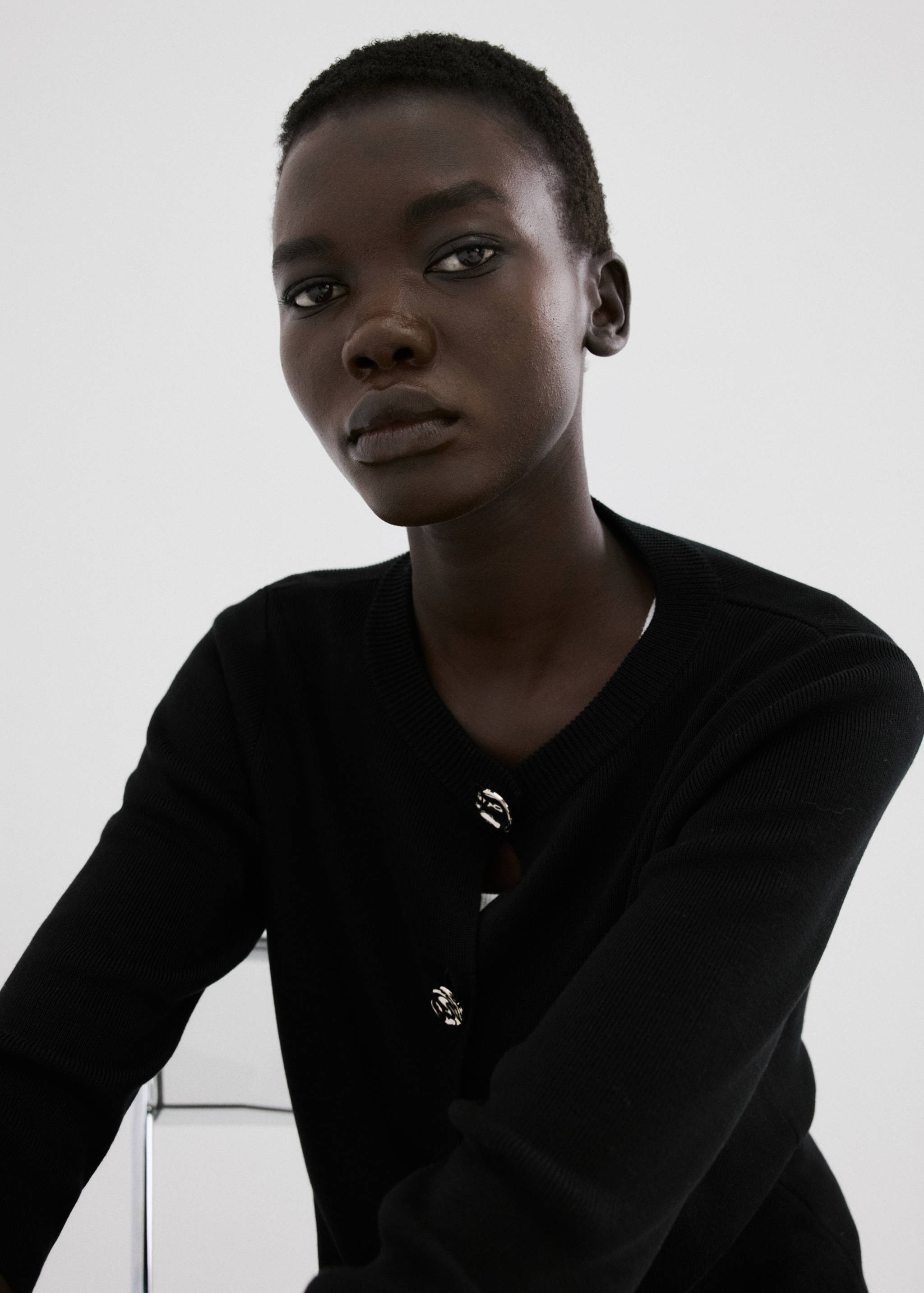 Black knitted cardigan with round neck and silver buttons.