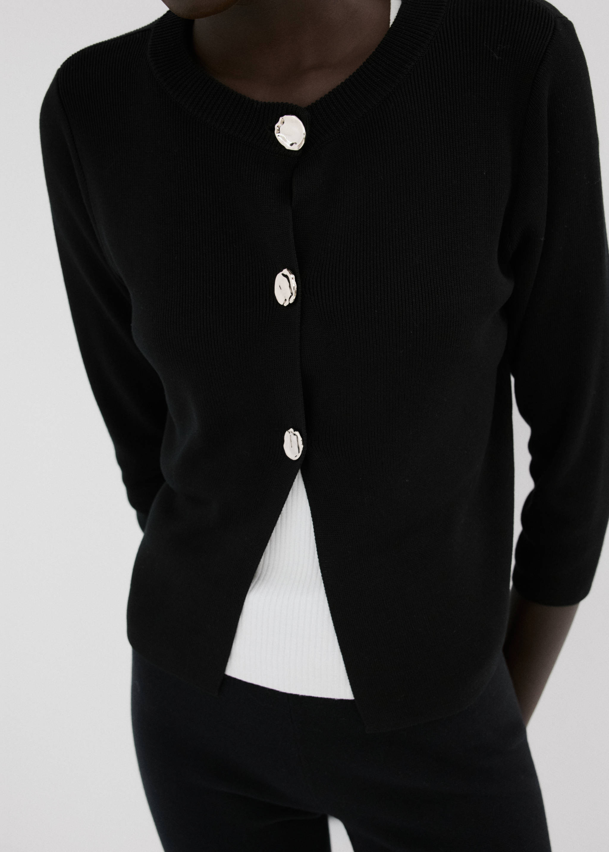 Black knitted cardigan with large metallic buttons and round neck.