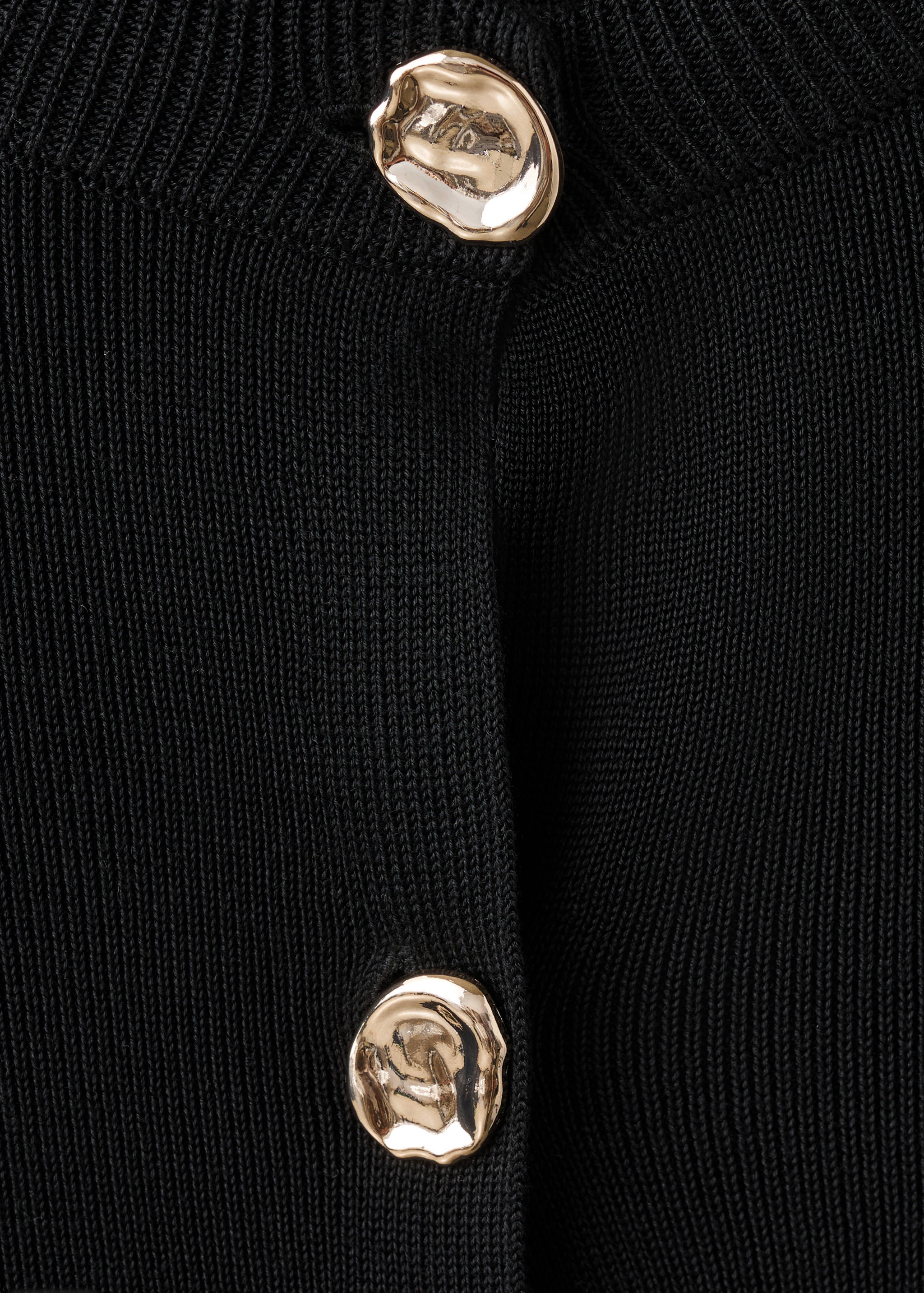 Close-up of a black cardigan with large gold metallic buttons.