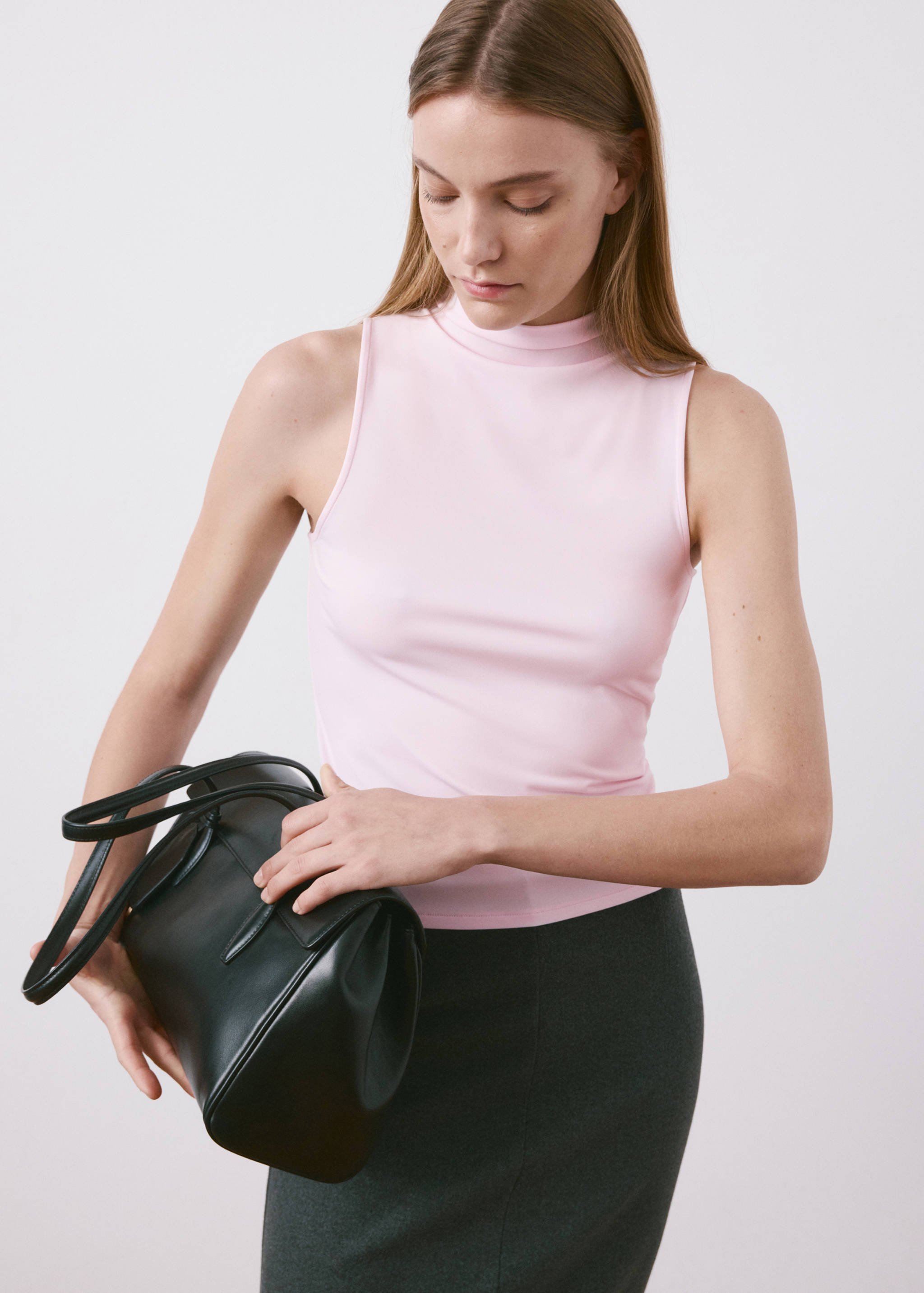 Top rosa sin mangas con cuello alto, combinado con una falda gris.