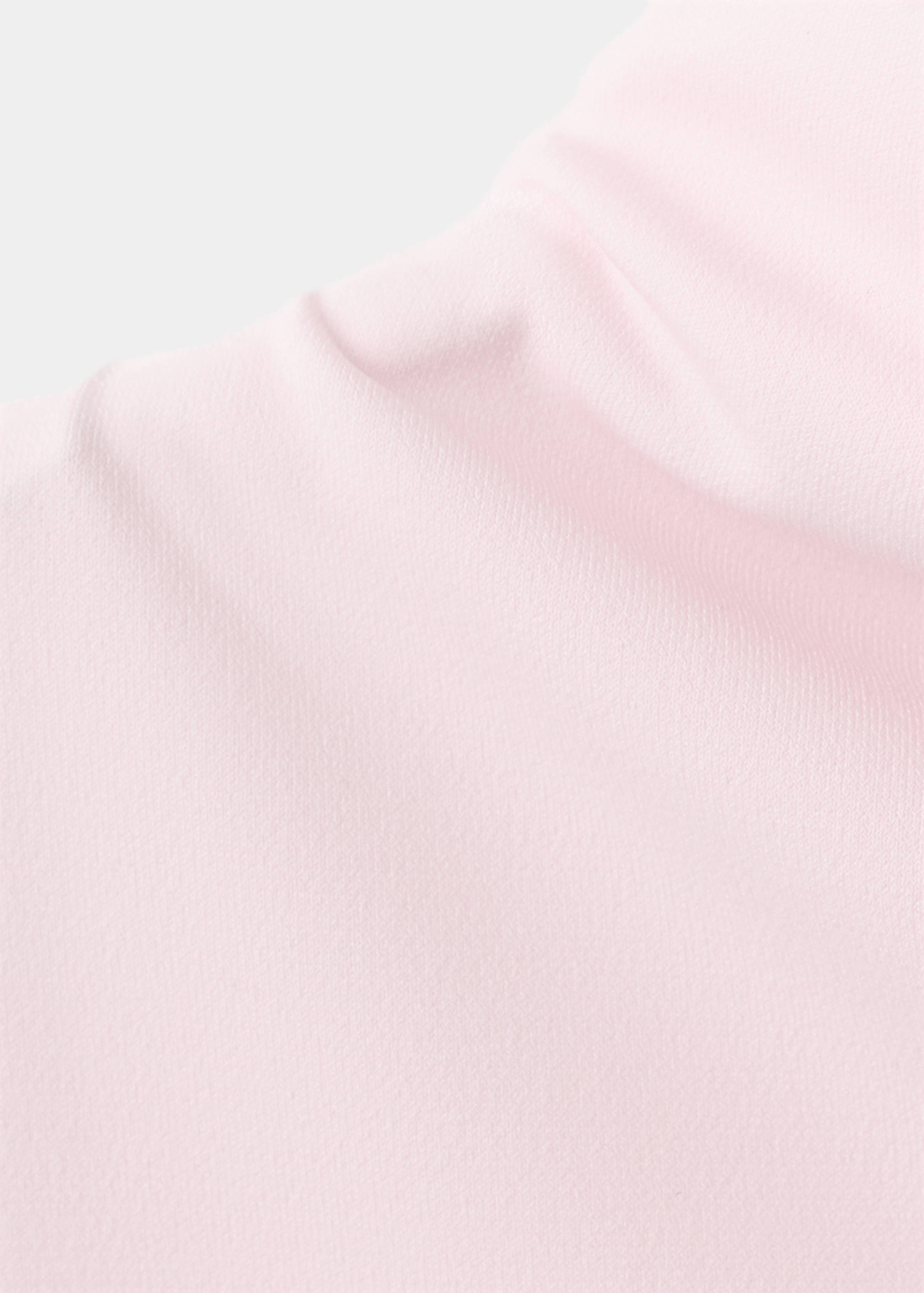 Primer plano del detalle de tejido en rosa claro de un top.