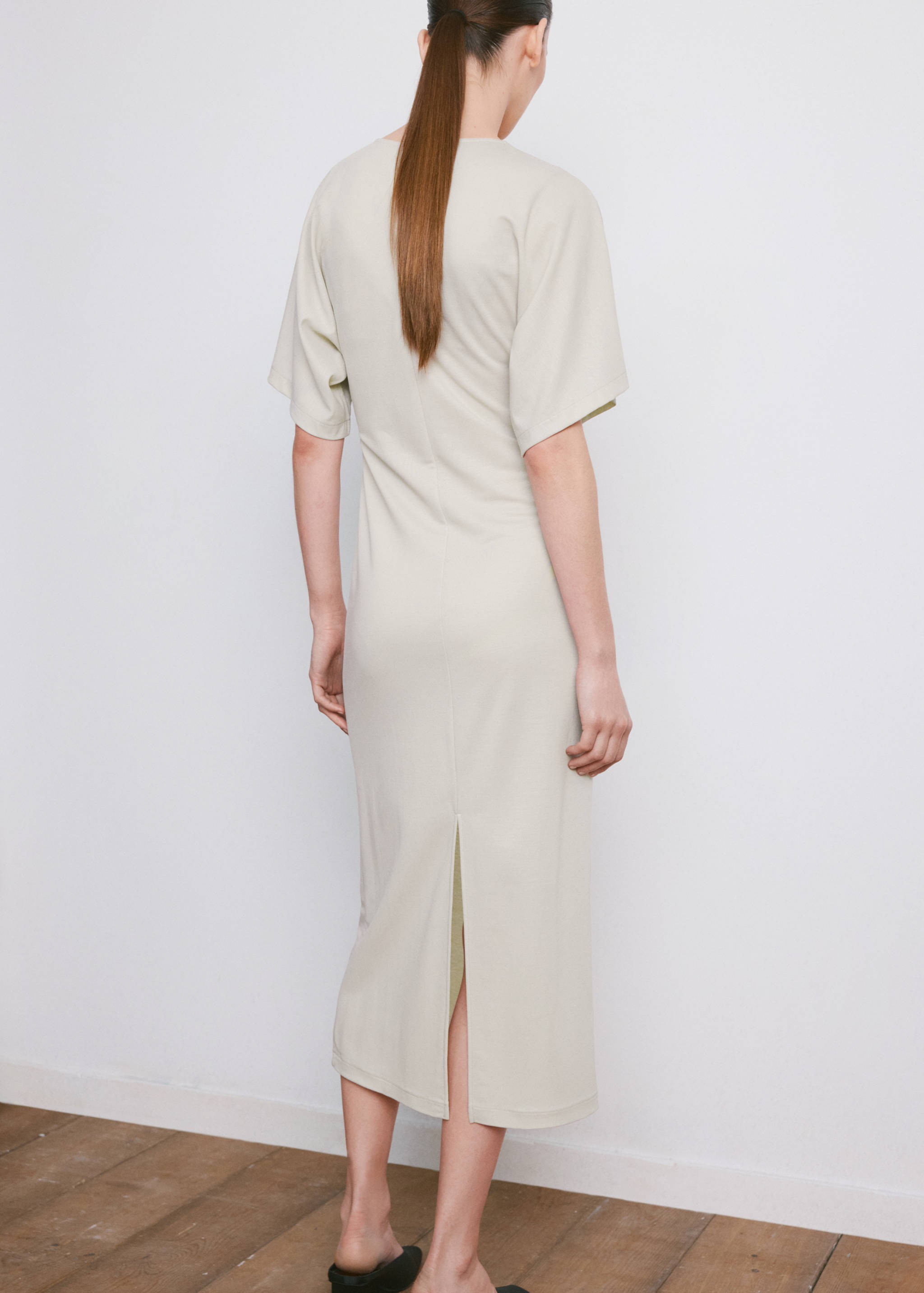 Light beige short-sleeved midi dress with a back slit, back view.