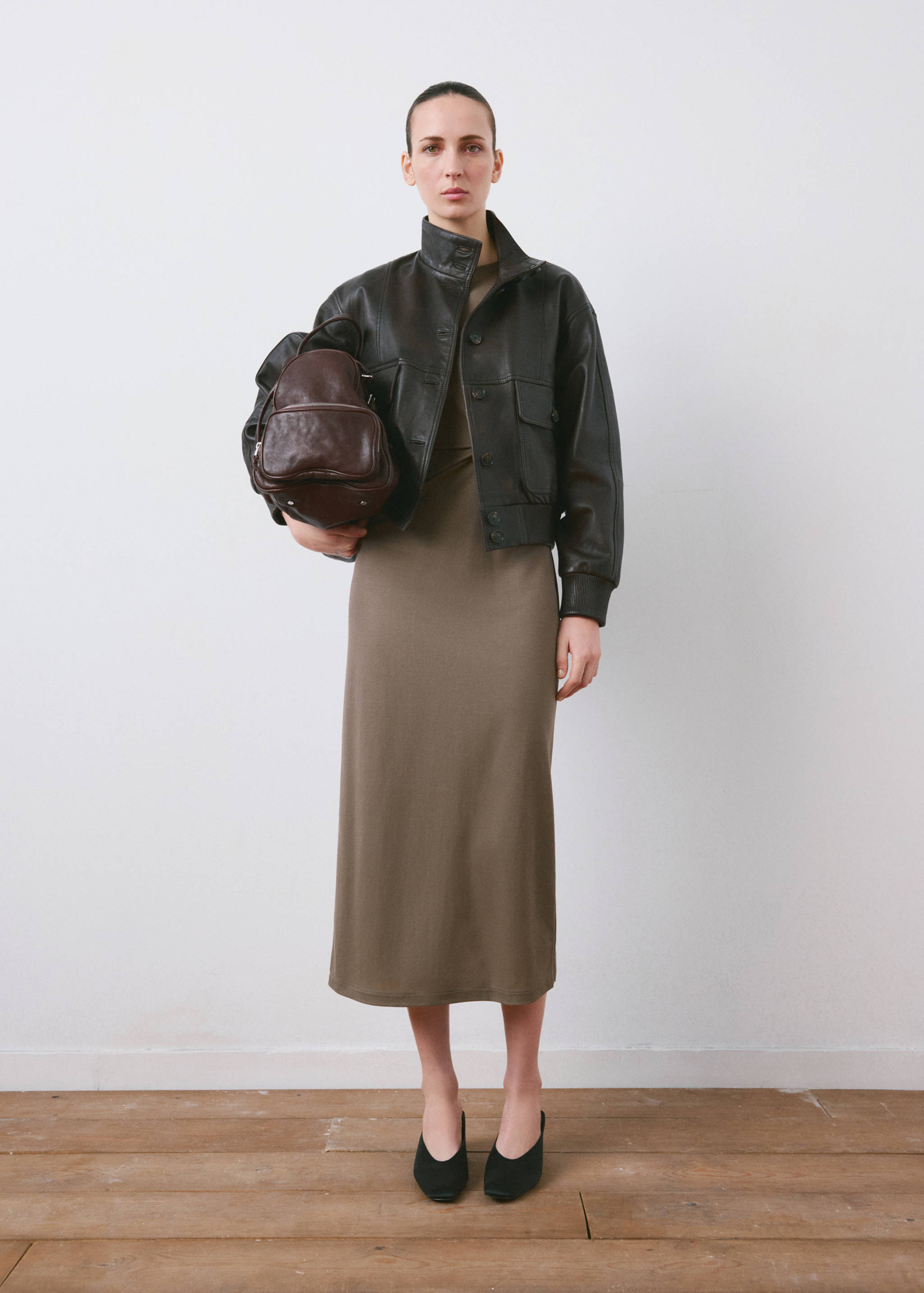 Khaki midi dress worn with a dark brown leather jacket and backpack.