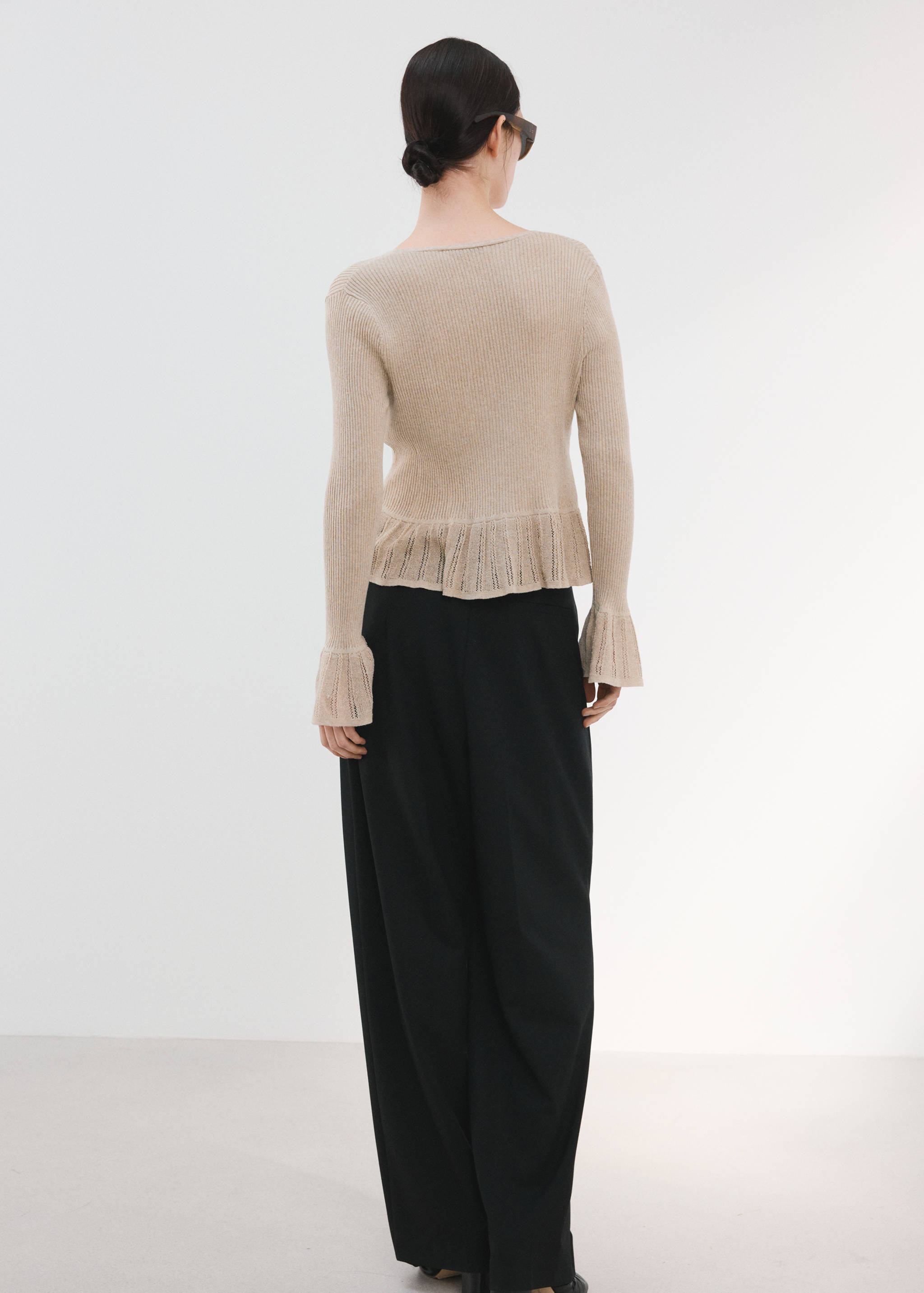 Beige ribbed cardigan with flared cuffs and hem, back view.