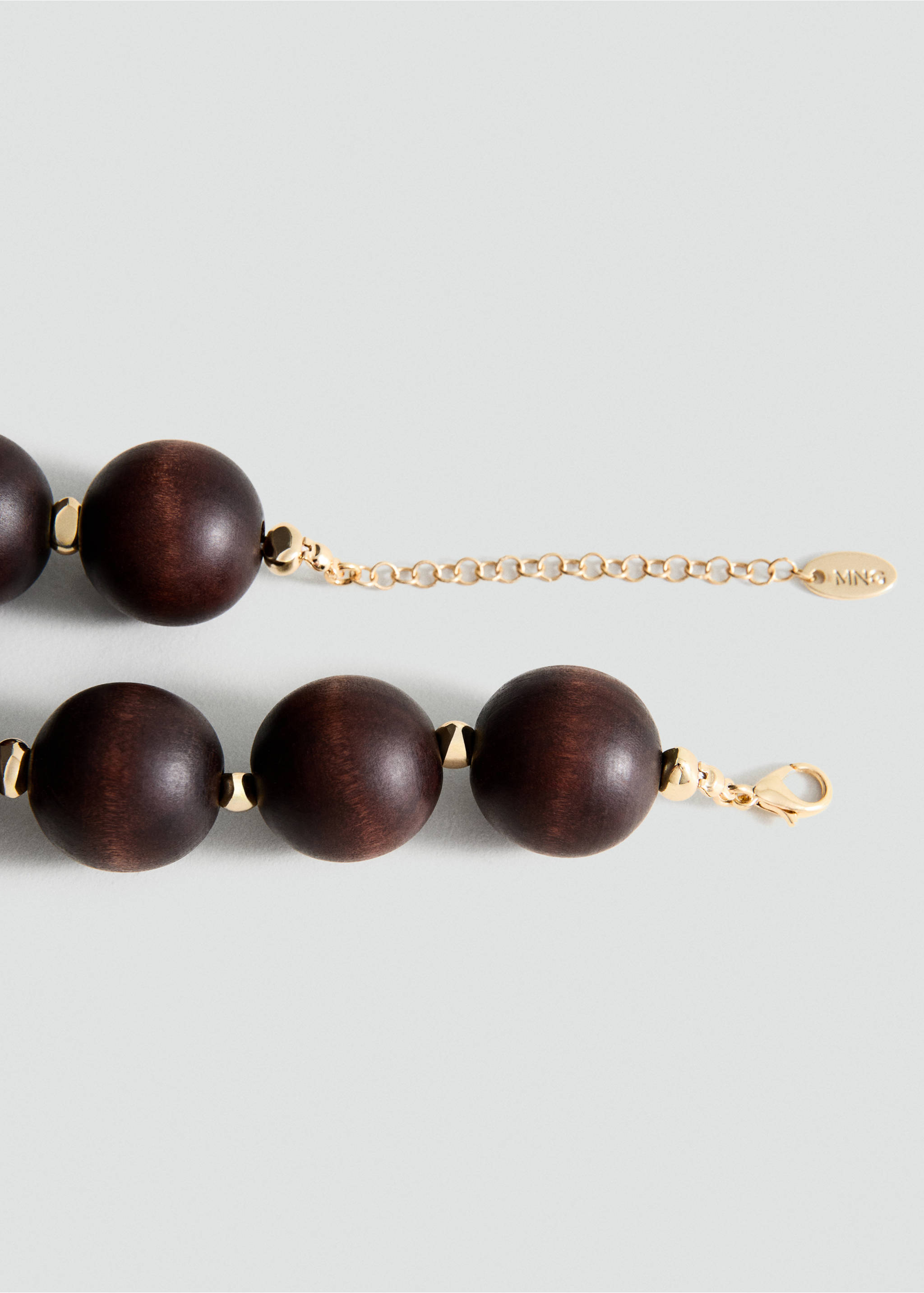Close-up of a dark brown wooden bead collar necklace with gold-toned metal spacers and an adjustable chain., Brown. Ref: 27055987-00.