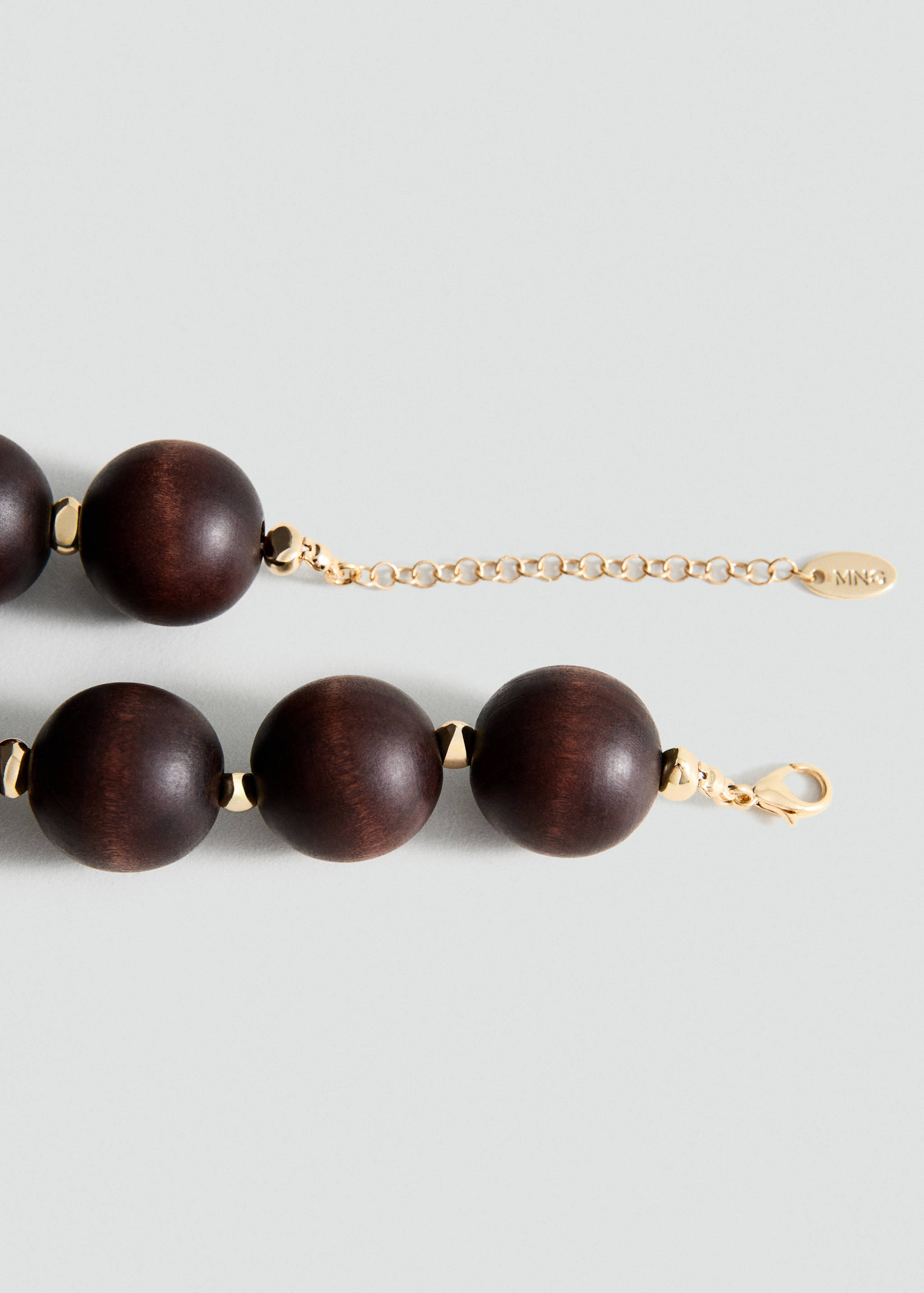 Close-up of a dark brown wooden bead collar necklace with gold-toned metal spacers and an adjustable chain.