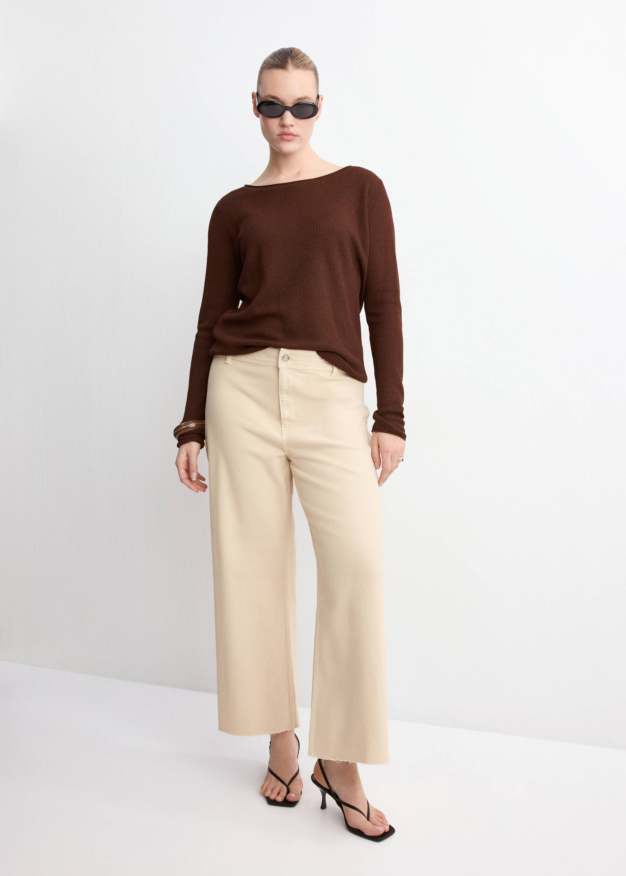 Beige wide-leg denim trousers with a raw hem, worn with a brown top.