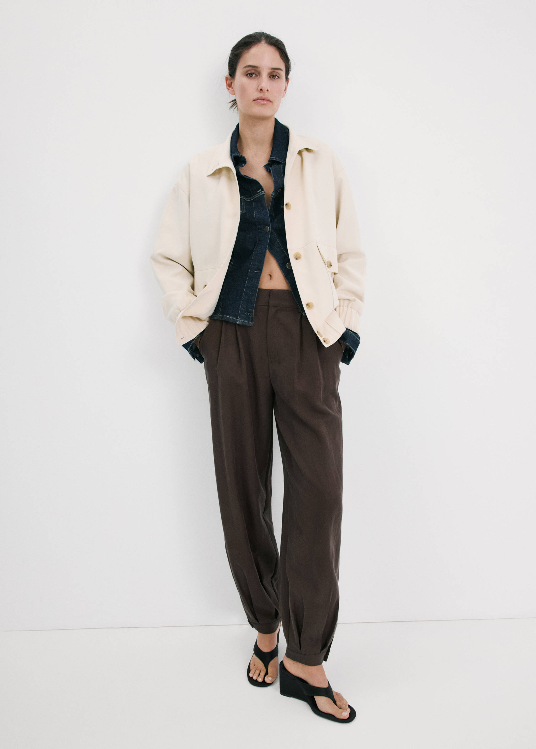 Chaqueta cruda con cierre de botones, combinada con camisa vaquera oscura y pantalones marrones