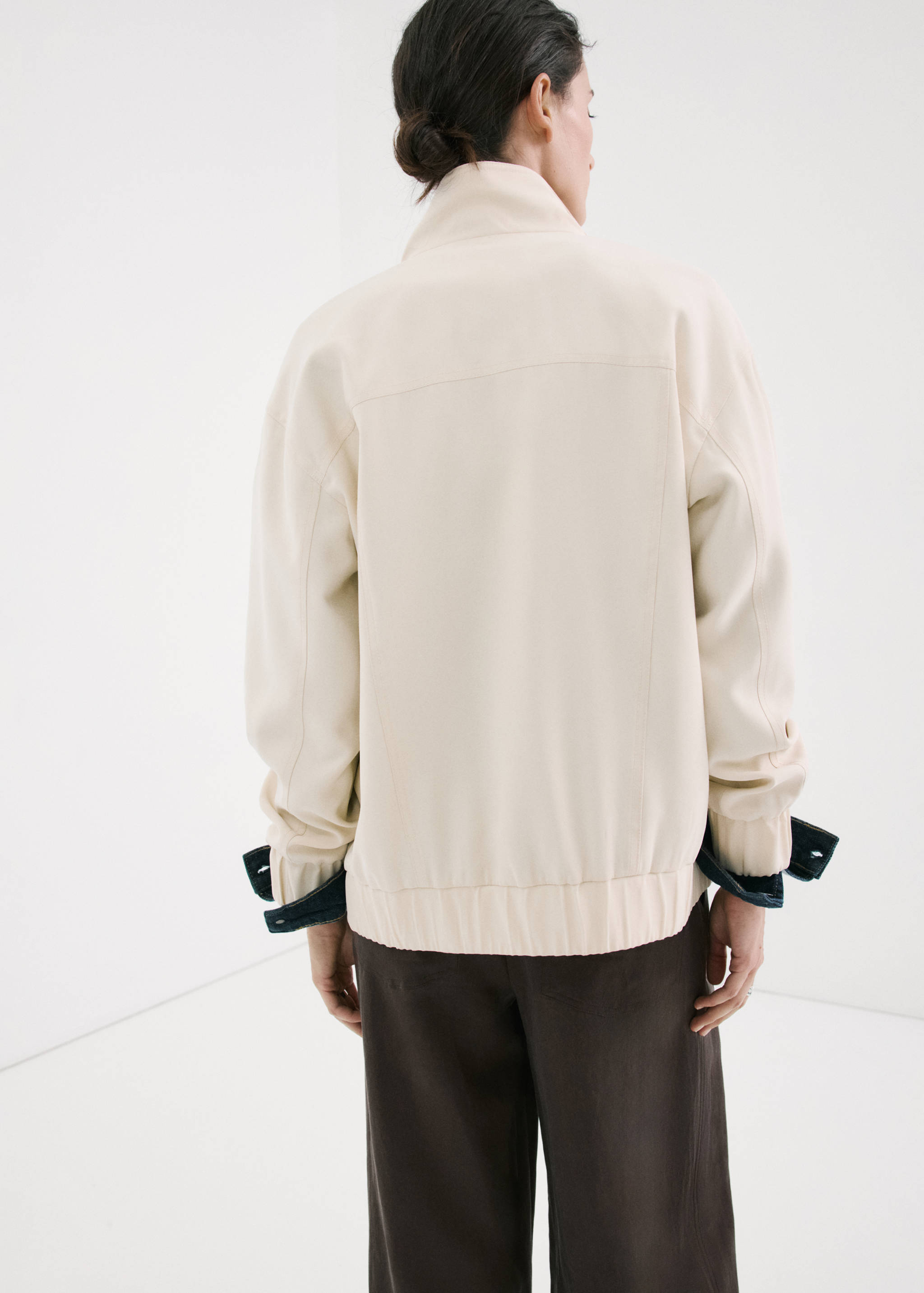 Chaquetas color crema, vista de espalda, con cuello alto y mangas con vuelta.