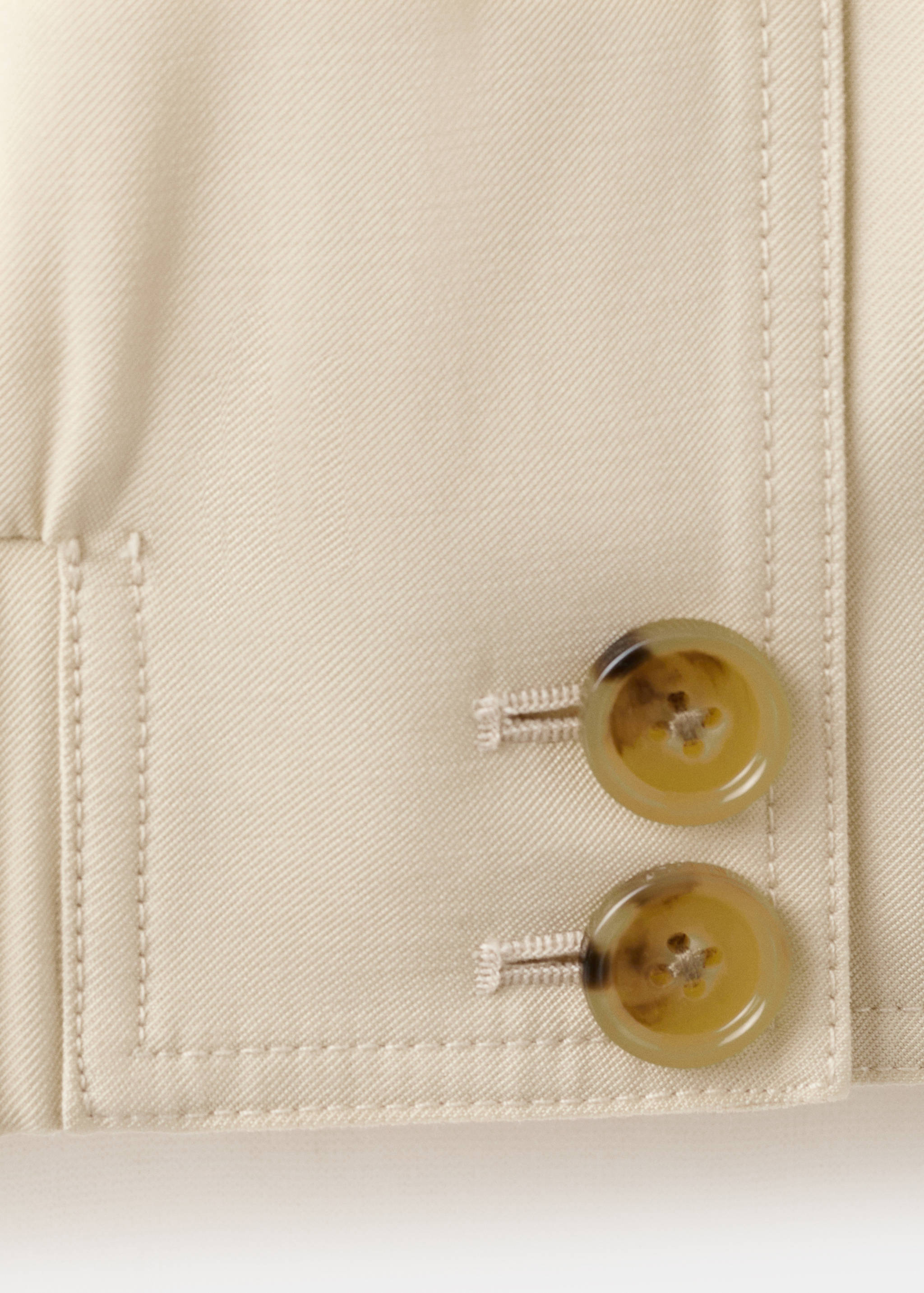 Detalle del puño de chaqueta beige con botones efecto carey