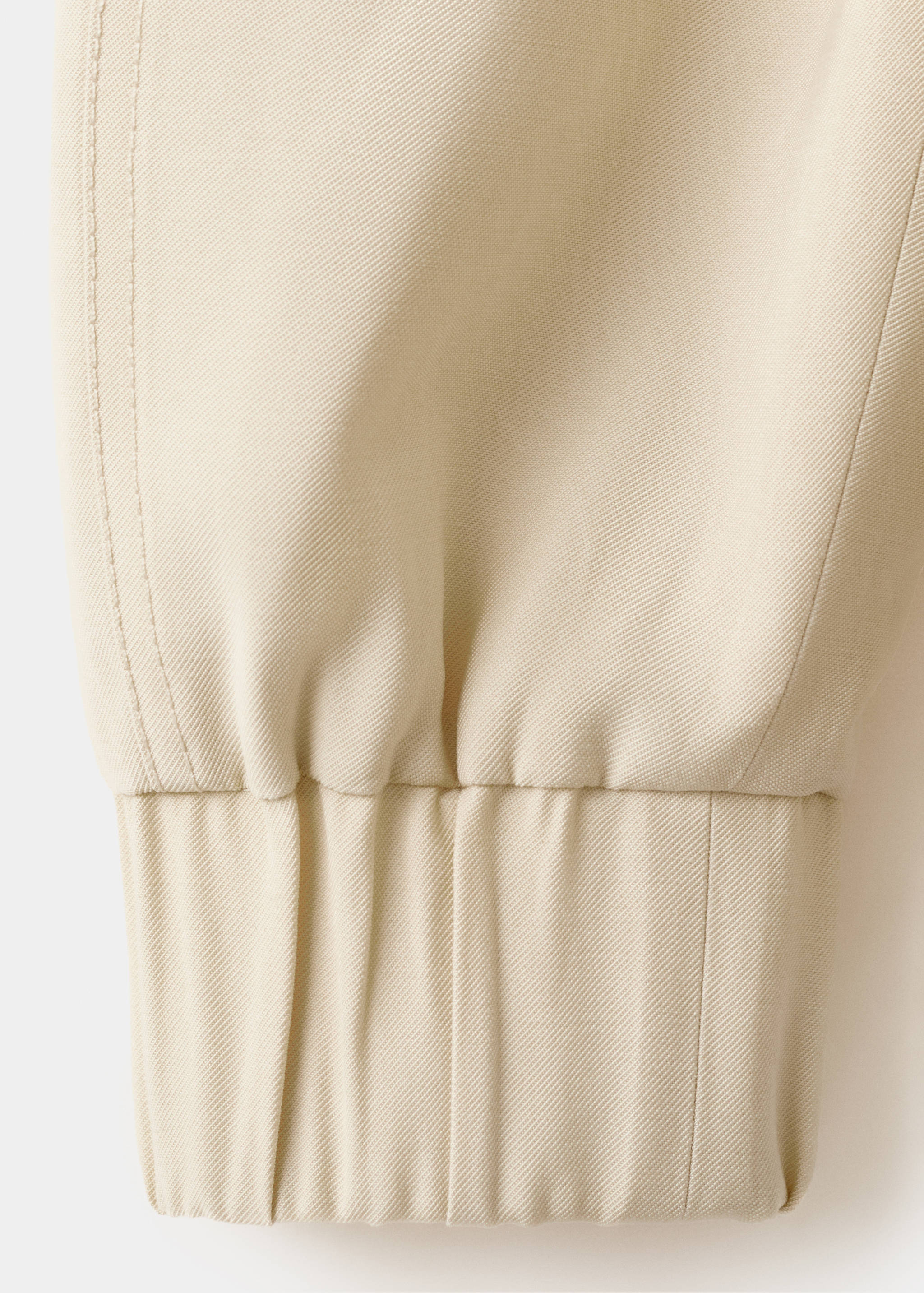 Detalle de la manga de la chaqueta beige con tejido cruzado y puño elástico.