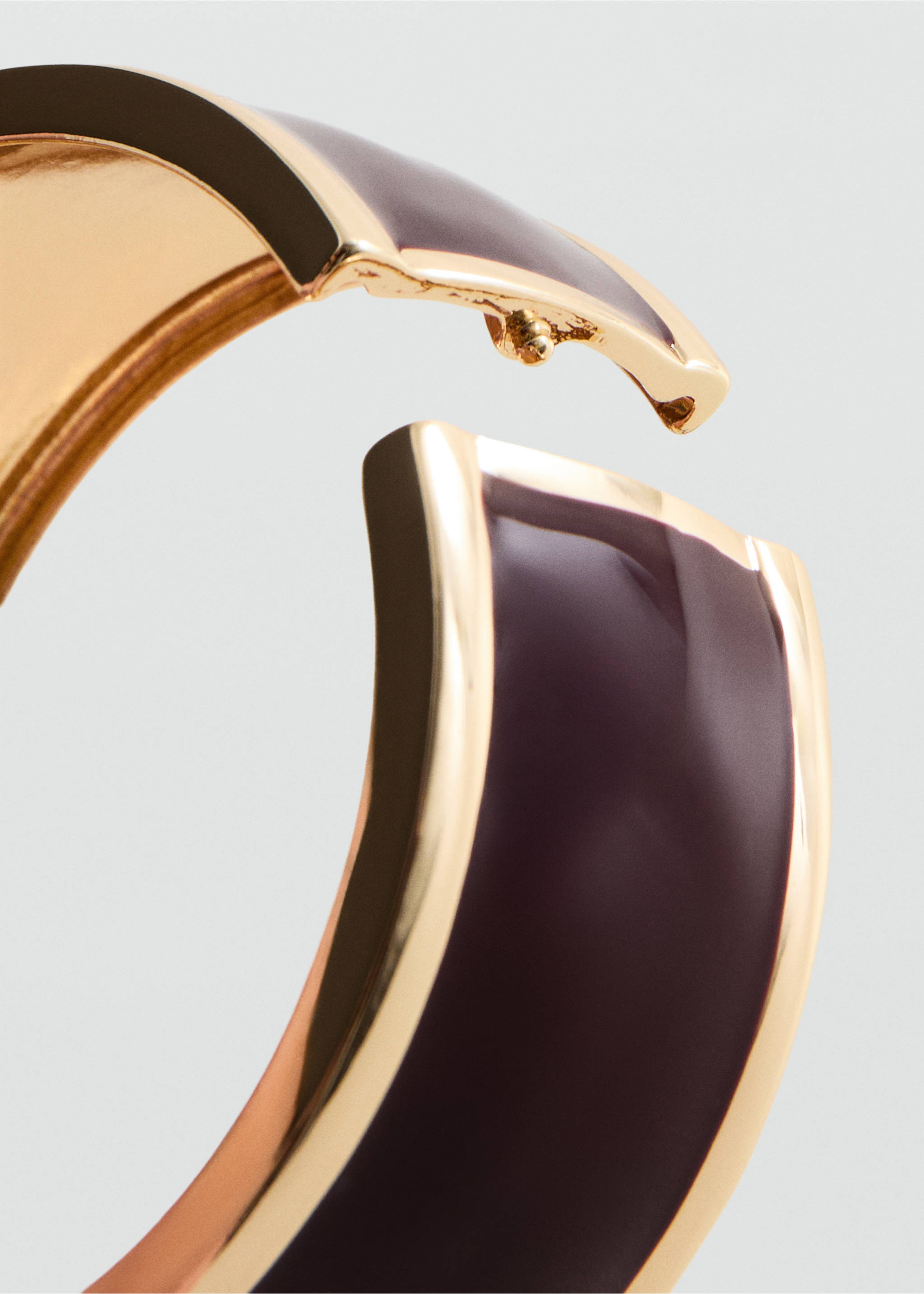 Primer plano de un brazalete rígido de metal en tono dorado con una inserción de esmalte en ciruela oscuro., Oro. Ref: 27065160-00.